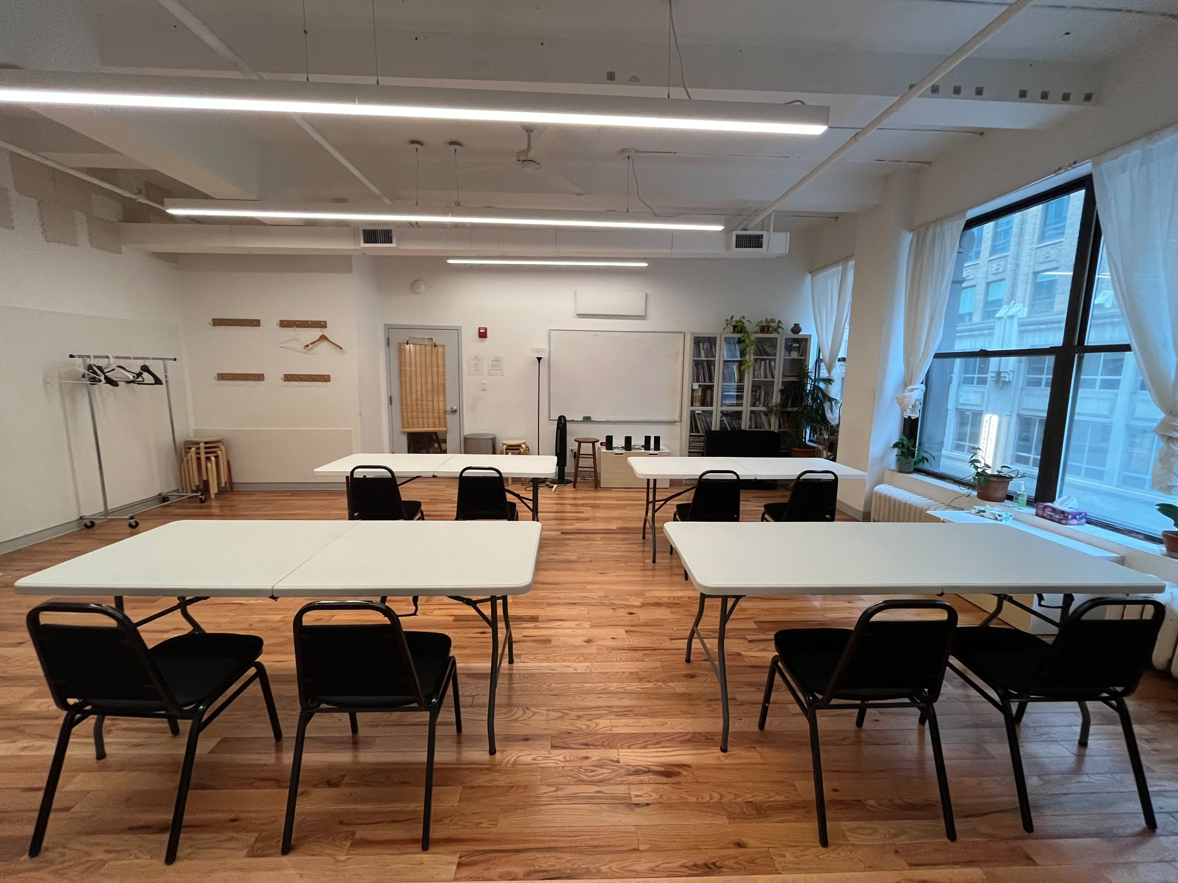 A workshop space is set up with chairs arranged in a circle, a keyboard on a stand, and large windows allowing natural light to fill the room.