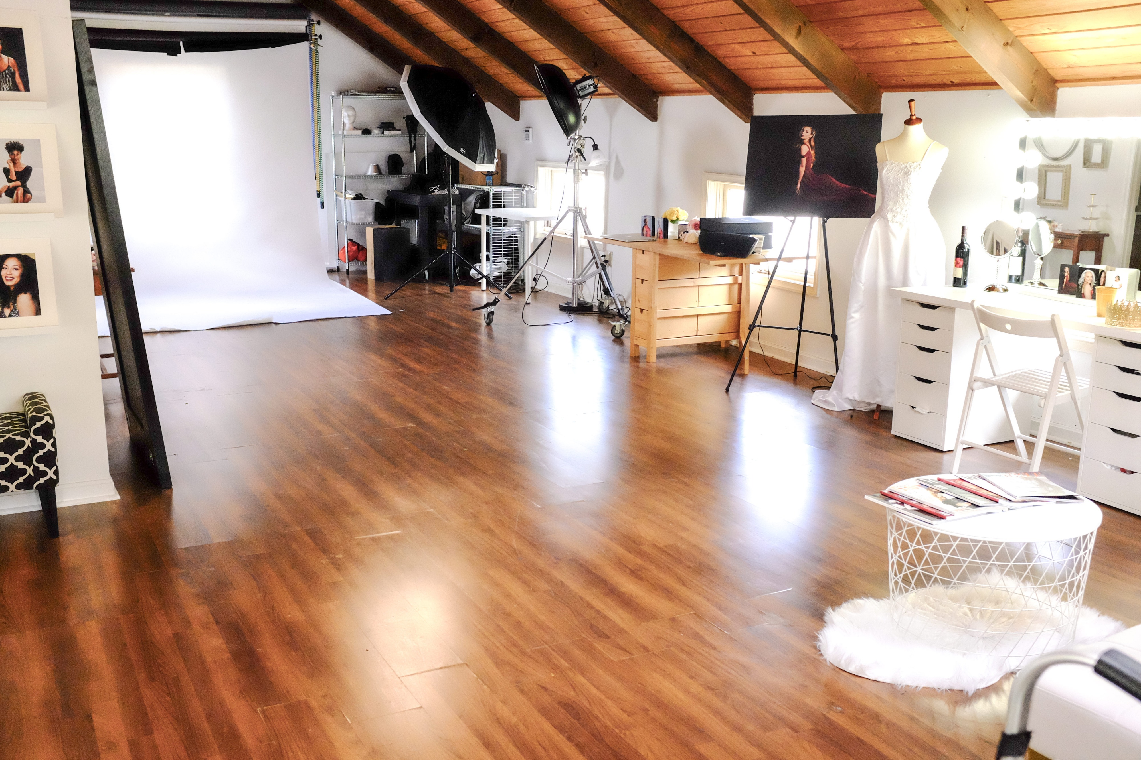 Three individuals pose together in a studio setting, surrounded by photography equipment and backdrops.