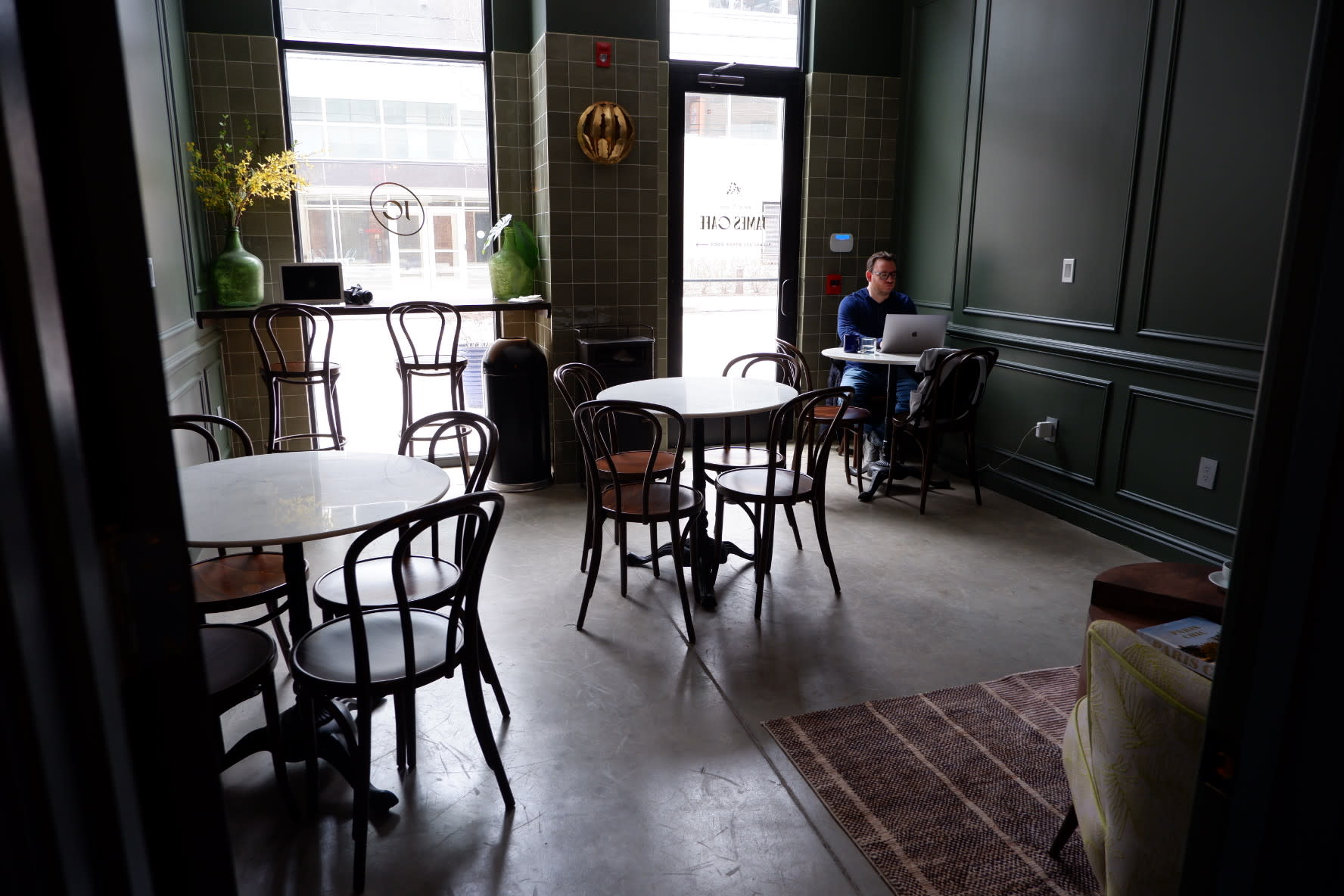 A latte sits on a marble table alongside a decorative napkin and a designer handbag.