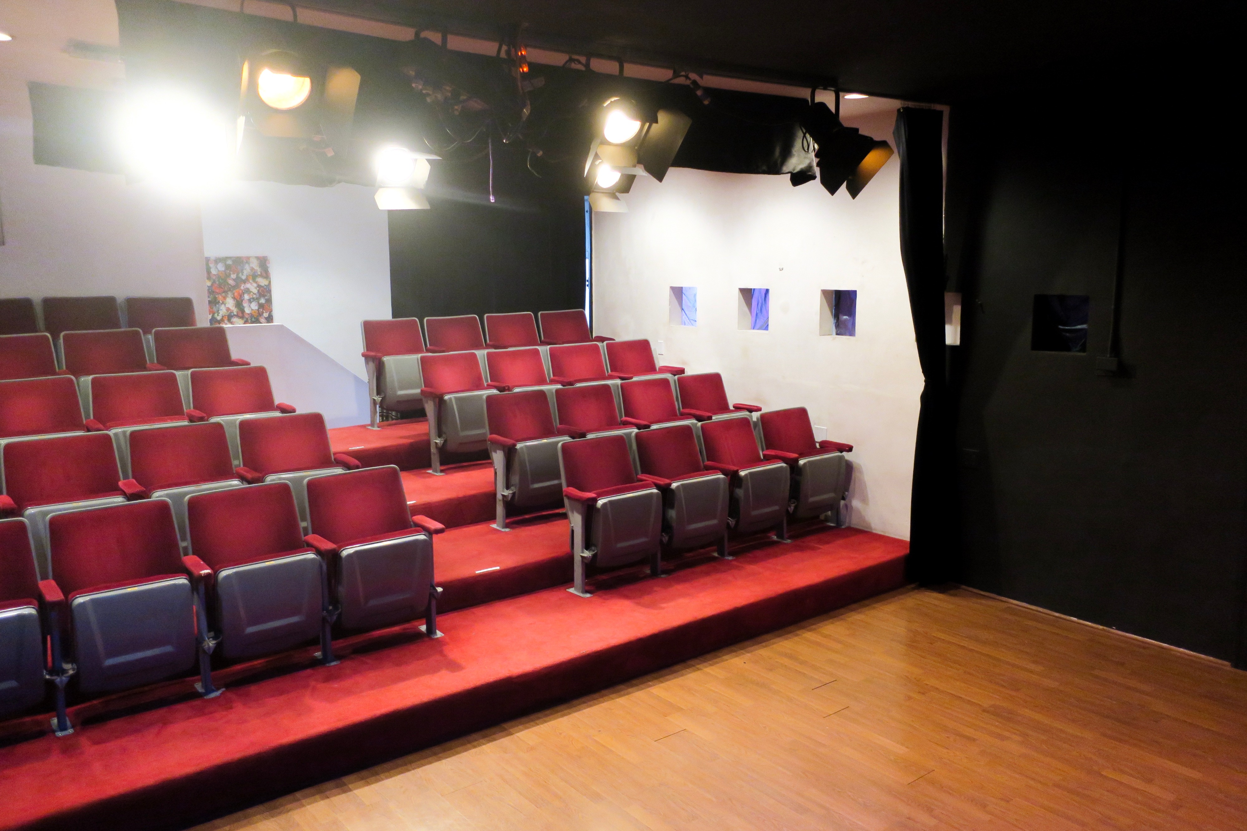A lone figure sits in an empty movie theater, surrounded by rows of vacant seats.