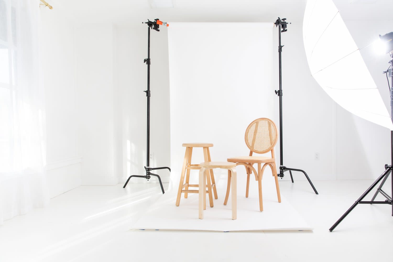 A photographer captures a model posing on a white backdrop during a photo shoot.