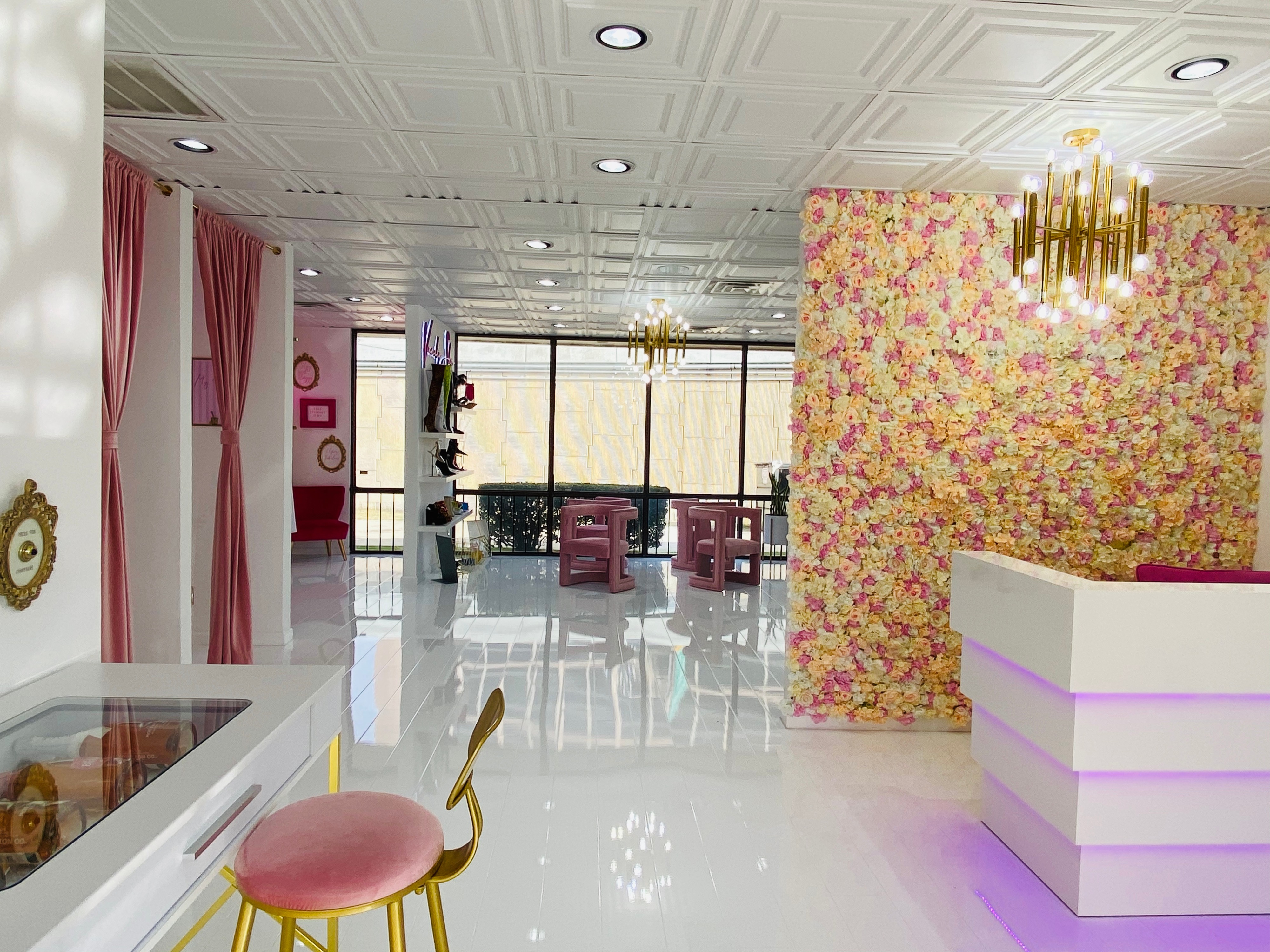 The scene features a brightly lit room decorated with a floral wall, showcasing a pink hanging chair surrounded by stylish accessories and a ring light set up for photo opportunities.