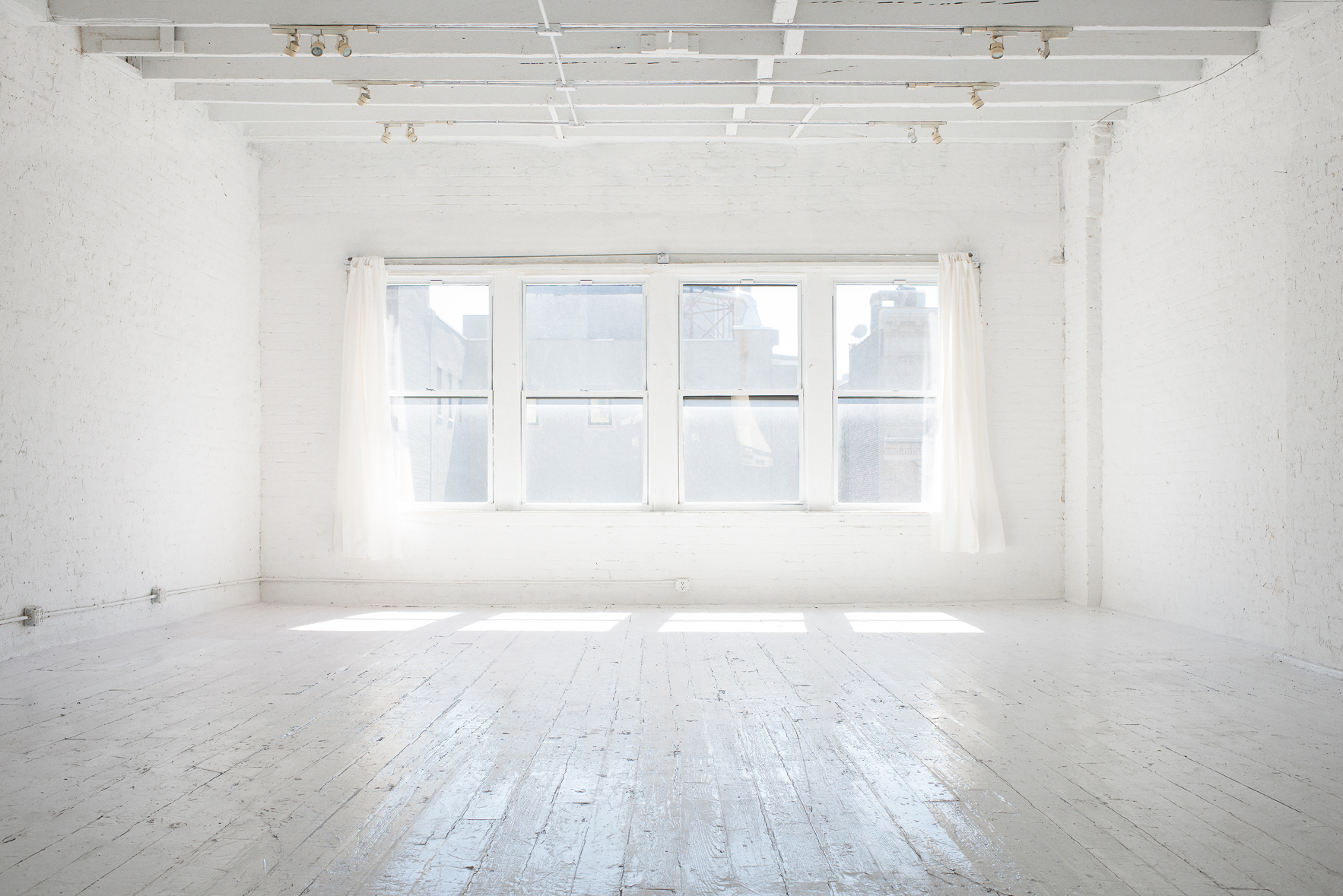 A photographer captures a model posing on a stool in a well-lit studio.