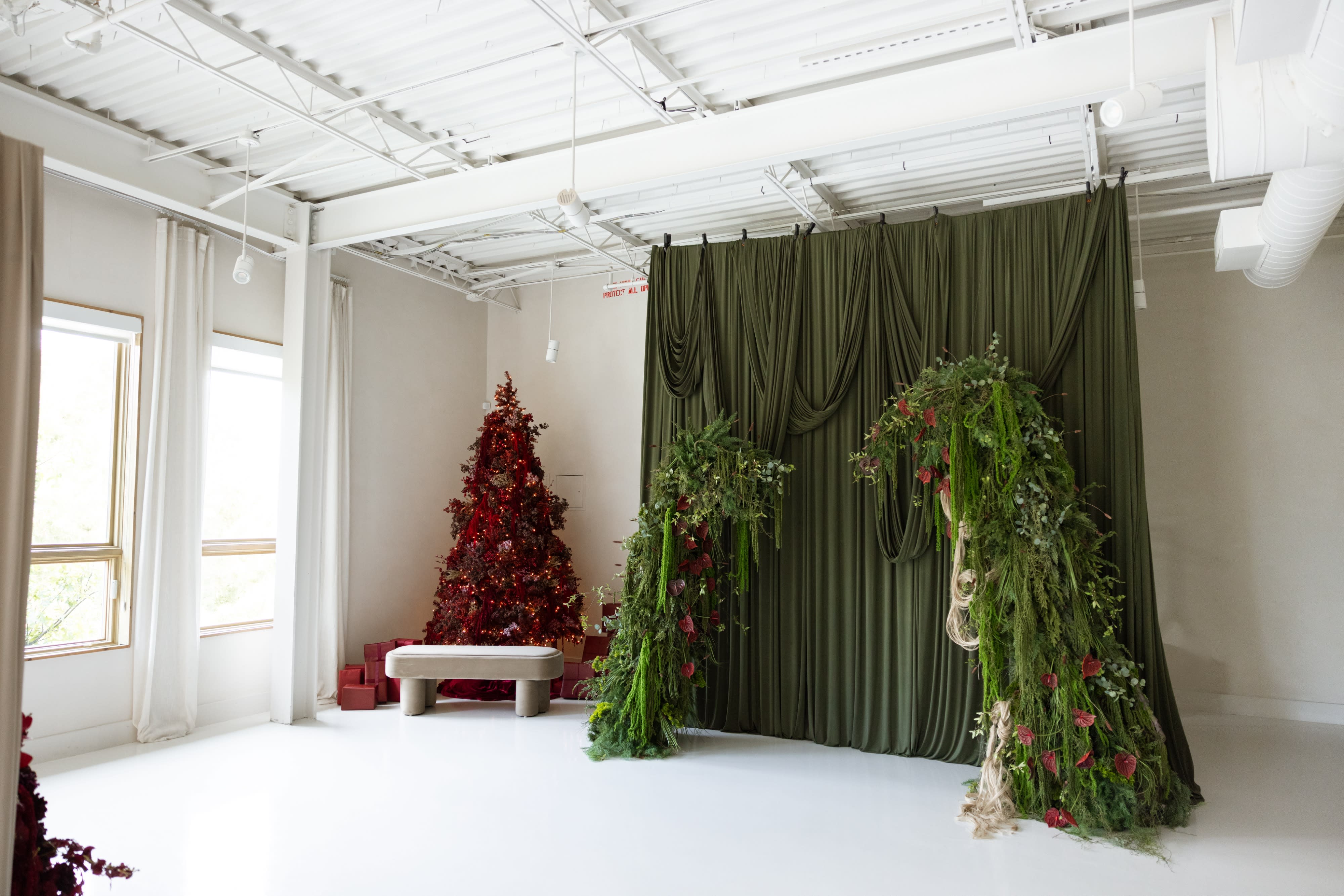 A model poses elegantly next to a sheer curtain in a bright, airy room.