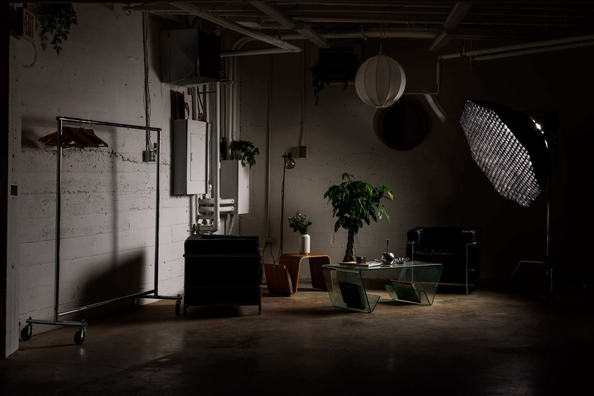 A person sits in a chair during a video shoot, surrounded by cameras and lighting equipment.