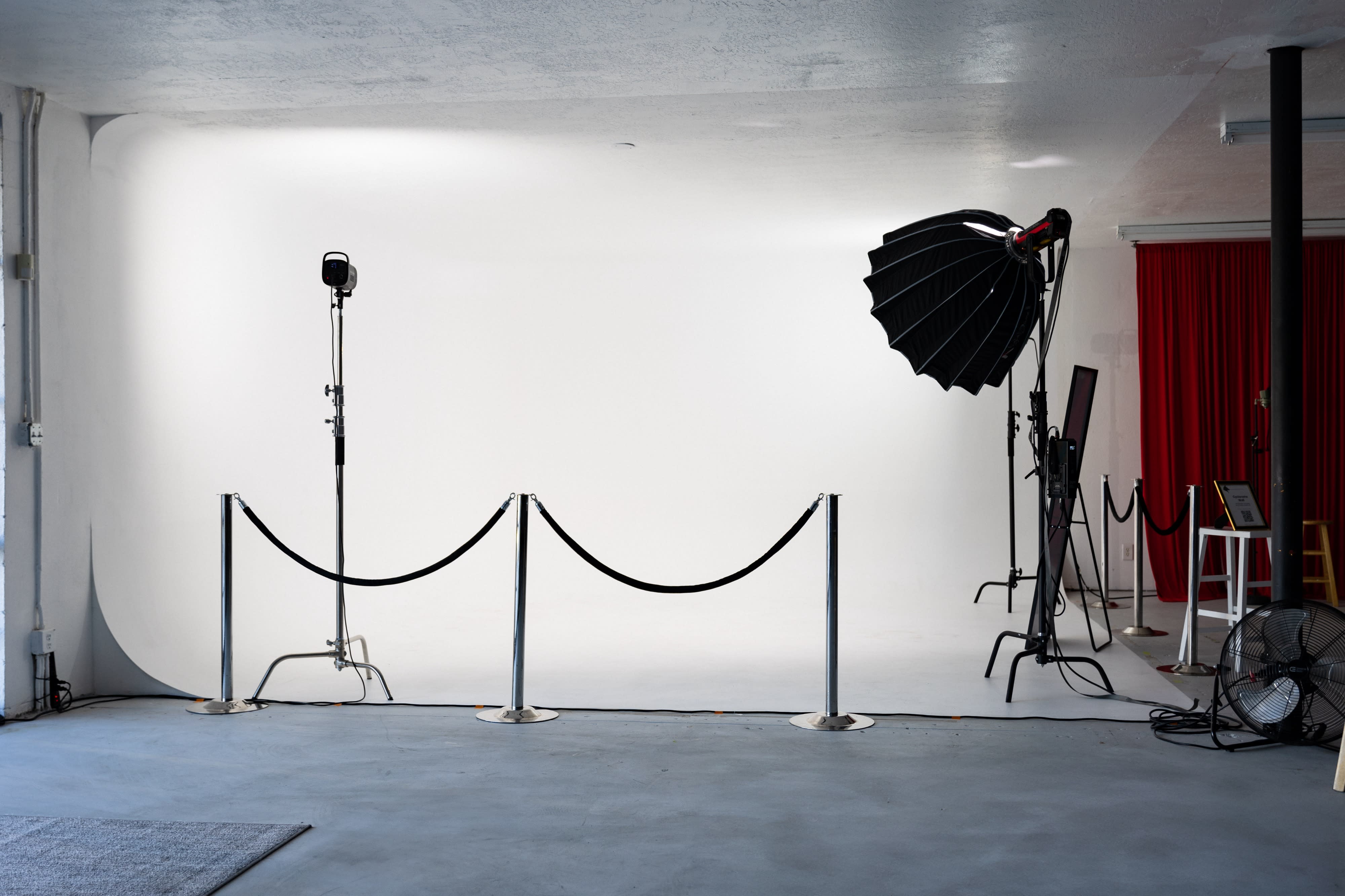 A woman sits in a square, white plush chair while a videographer captures the scene from in front.