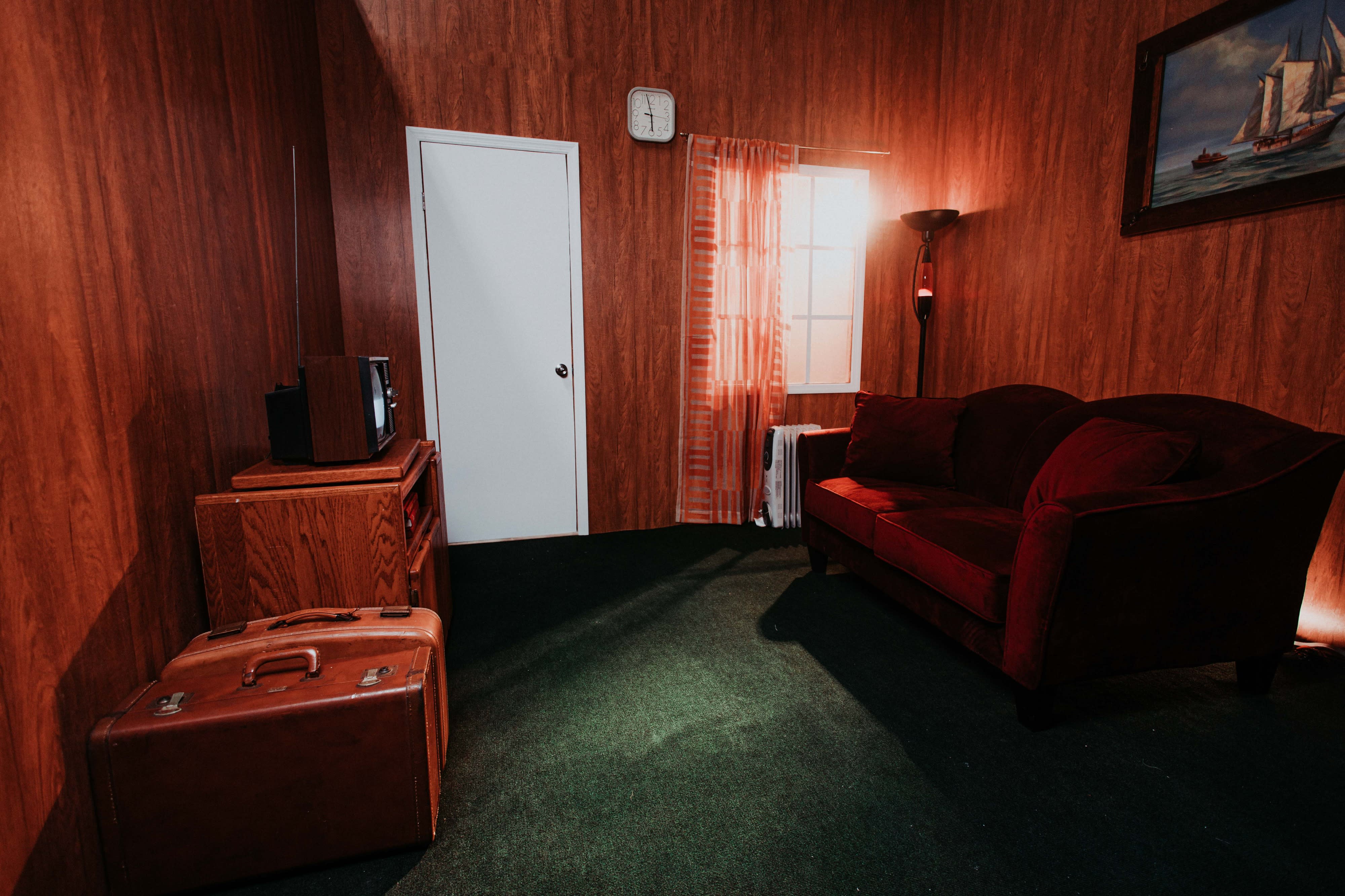 Two women are posing in a retro living room while playing video games on a couch.