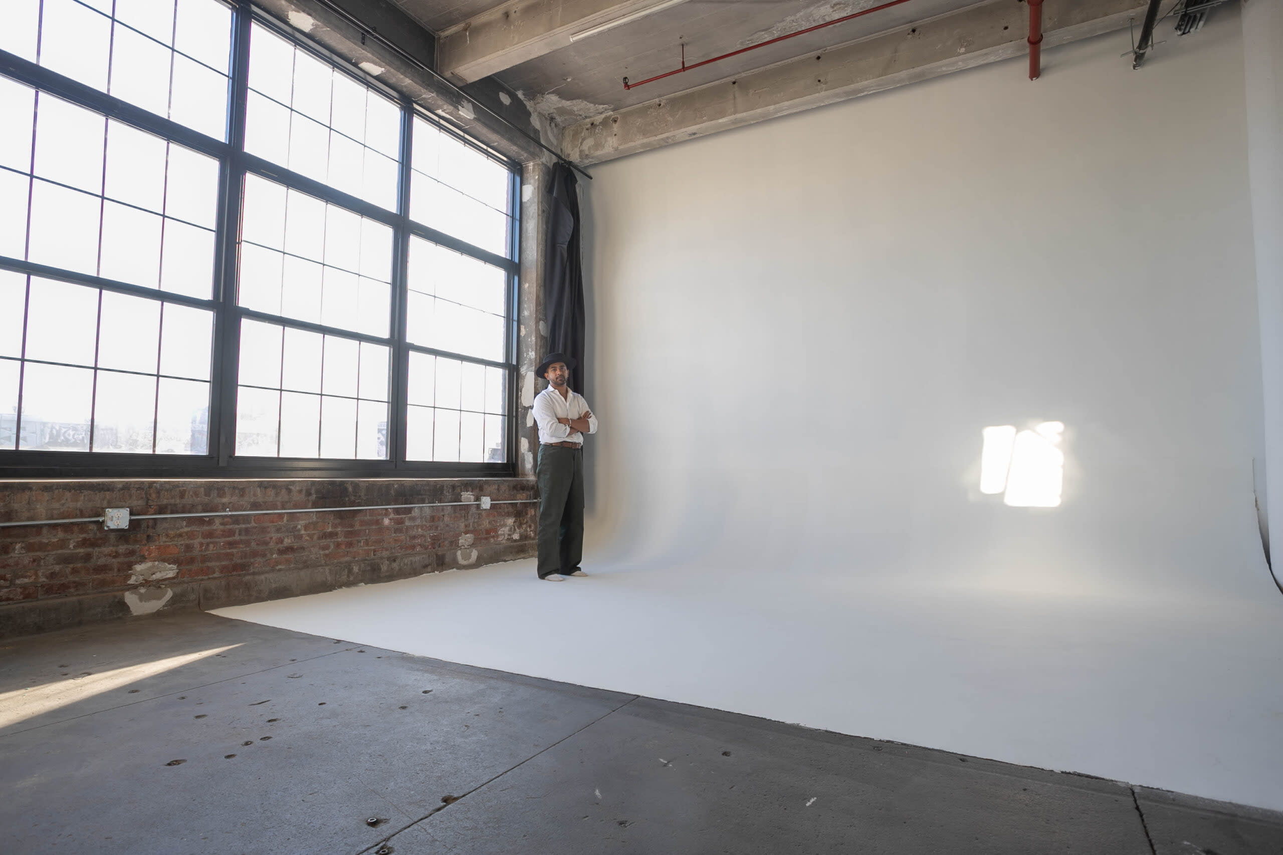 A dancer performs a high kick during a rehearsal in a bright, empty studio.