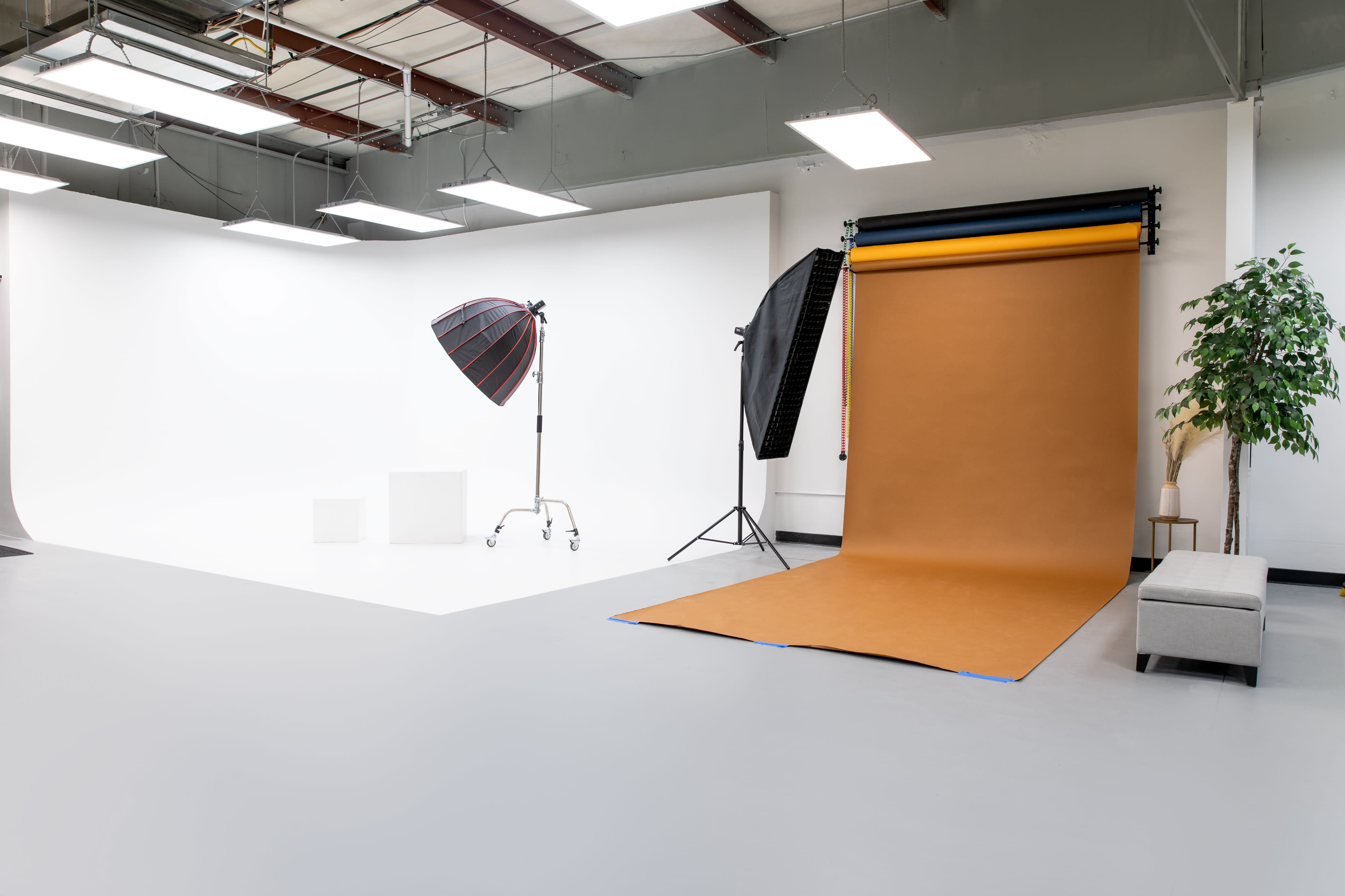 A model poses on a white cube wearing a patterned outfit and knee-high white boots against a plain backdrop.