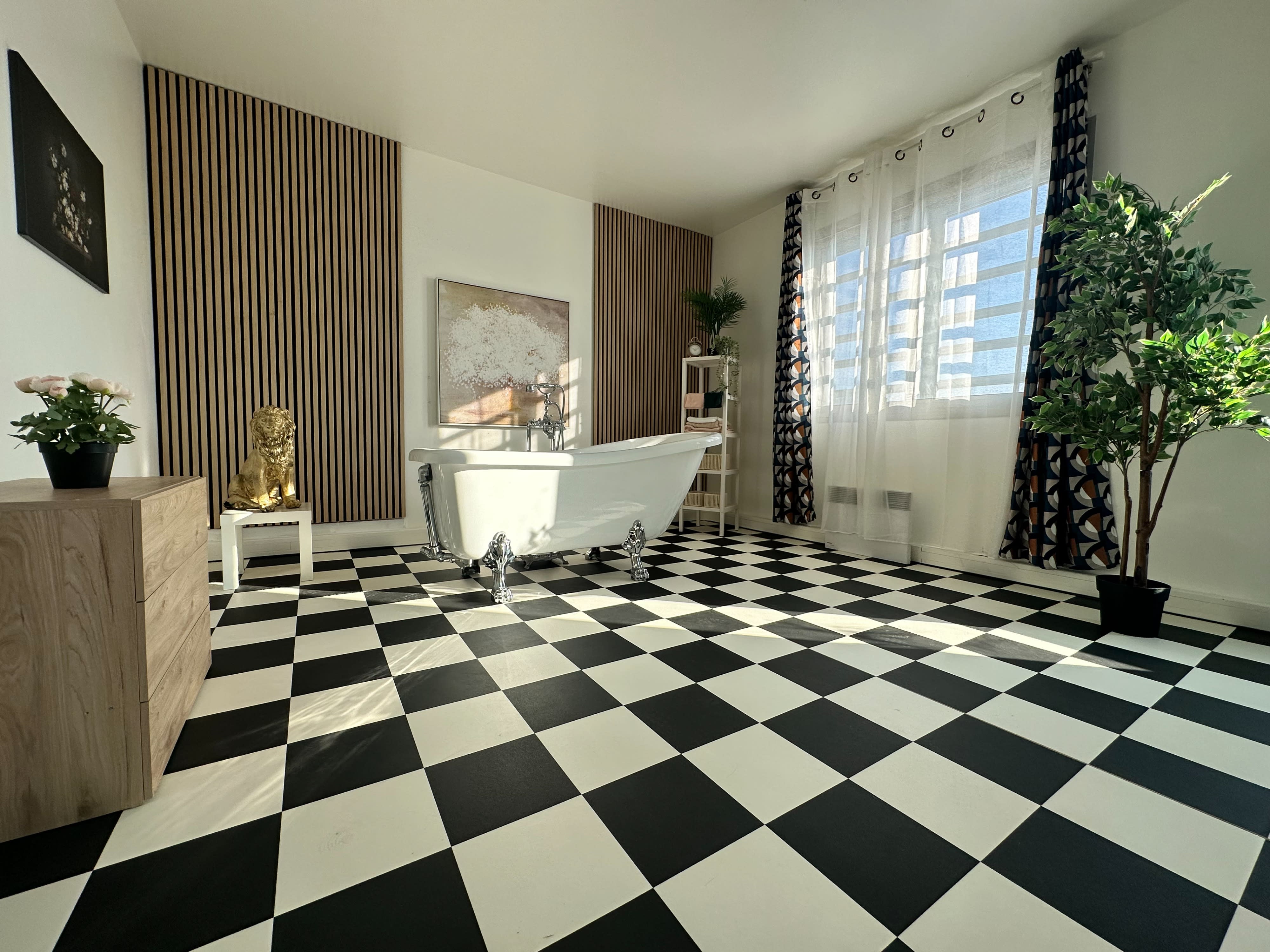 A person lies on a checkered floor in a bathroom setting, dressed in a black outfit with fishnet stockings.
