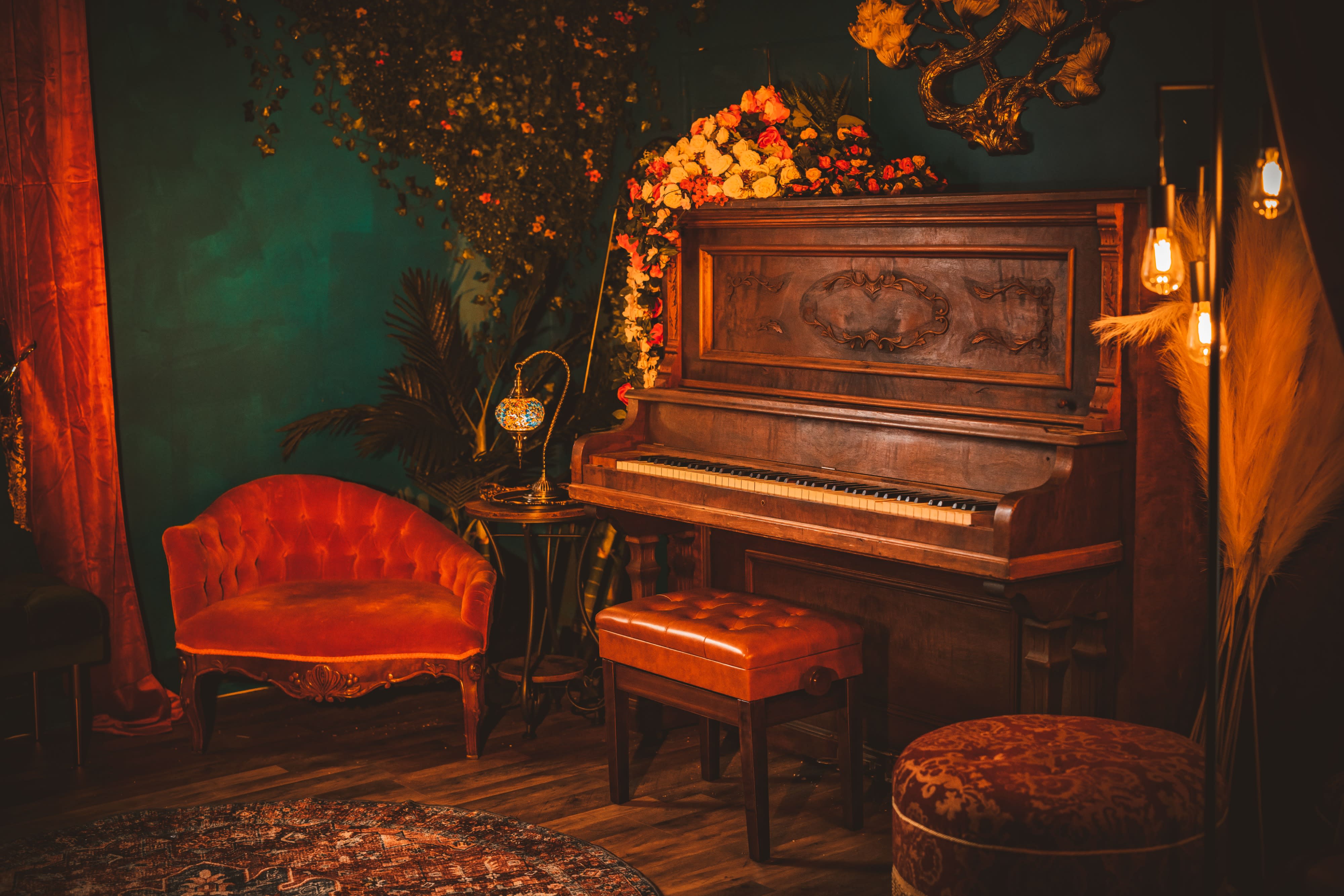 A person is posed upside down on a leather couch in a dimly lit studio, with candles illuminating the scene.