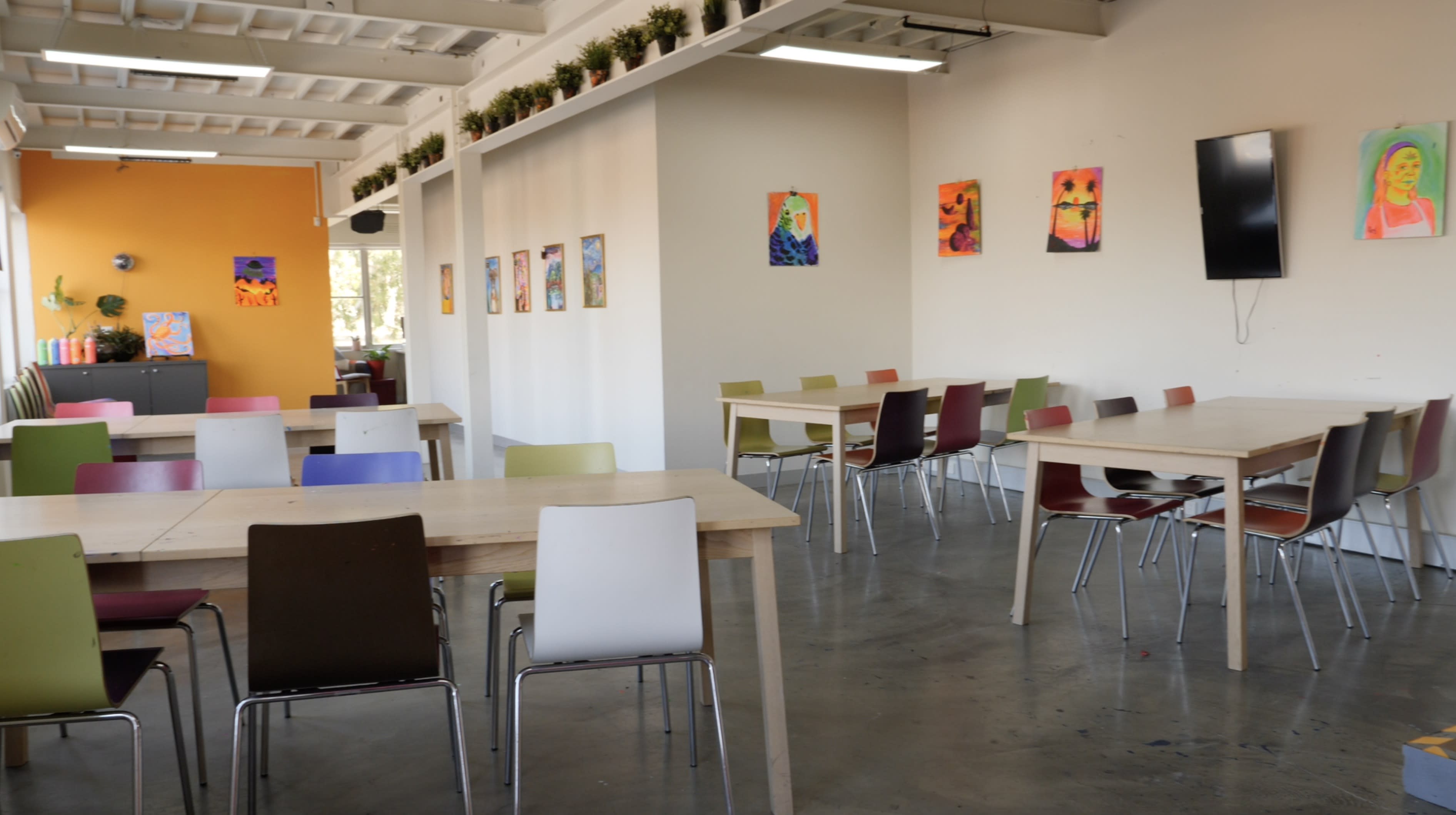 A group of individuals gathers around a table, engaged in crafting and decorating projects with stickers and supplies.