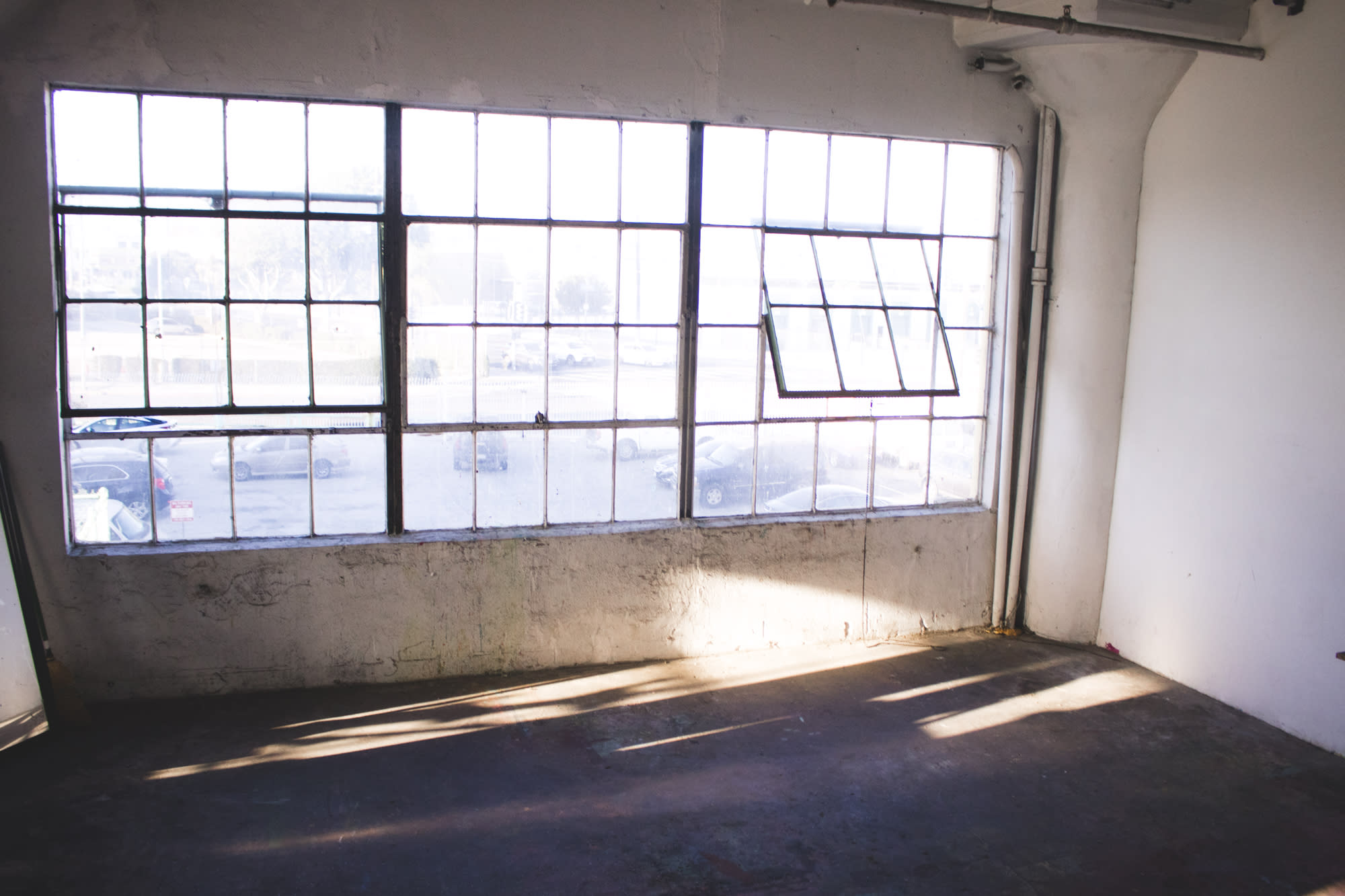 A person films a silver mannequin covered in graffiti in a bare, well-lit room.