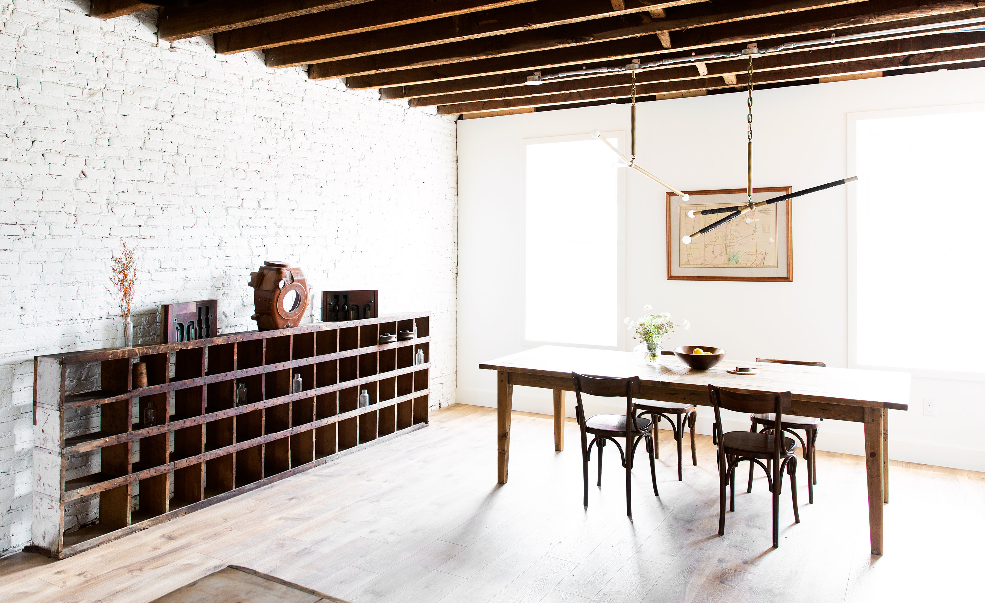 A styled arrangement of vases and a pitcher on a wooden shelf against a brick wall.