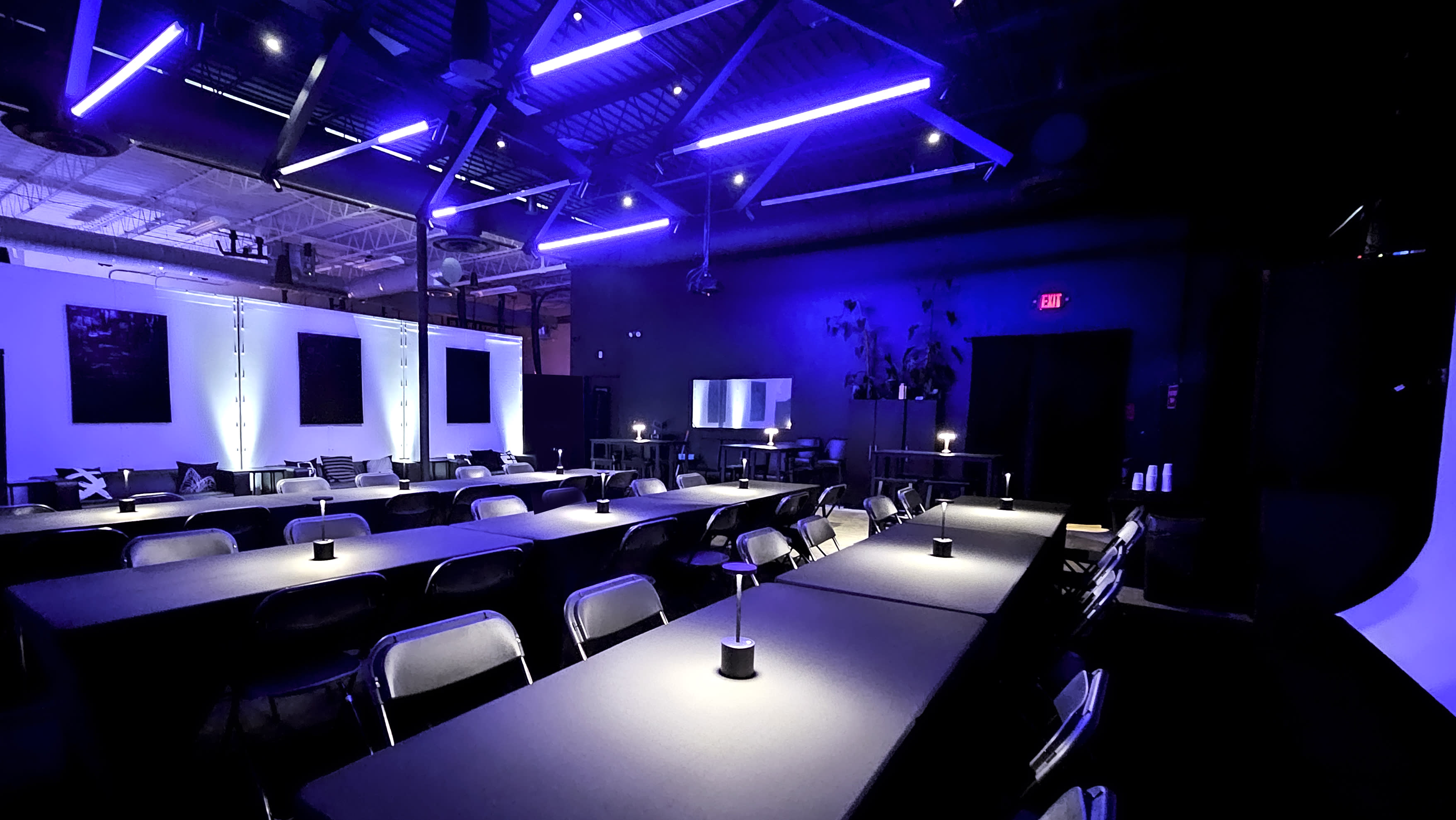 A presenter demonstrates a product on a large screen to an audience seated in chairs in a modern, well-lit space.