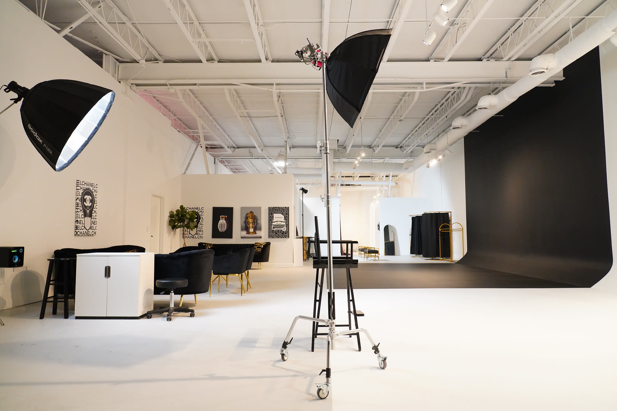A photographer captures a makeup artist applying makeup on a model in a well-lit studio.
