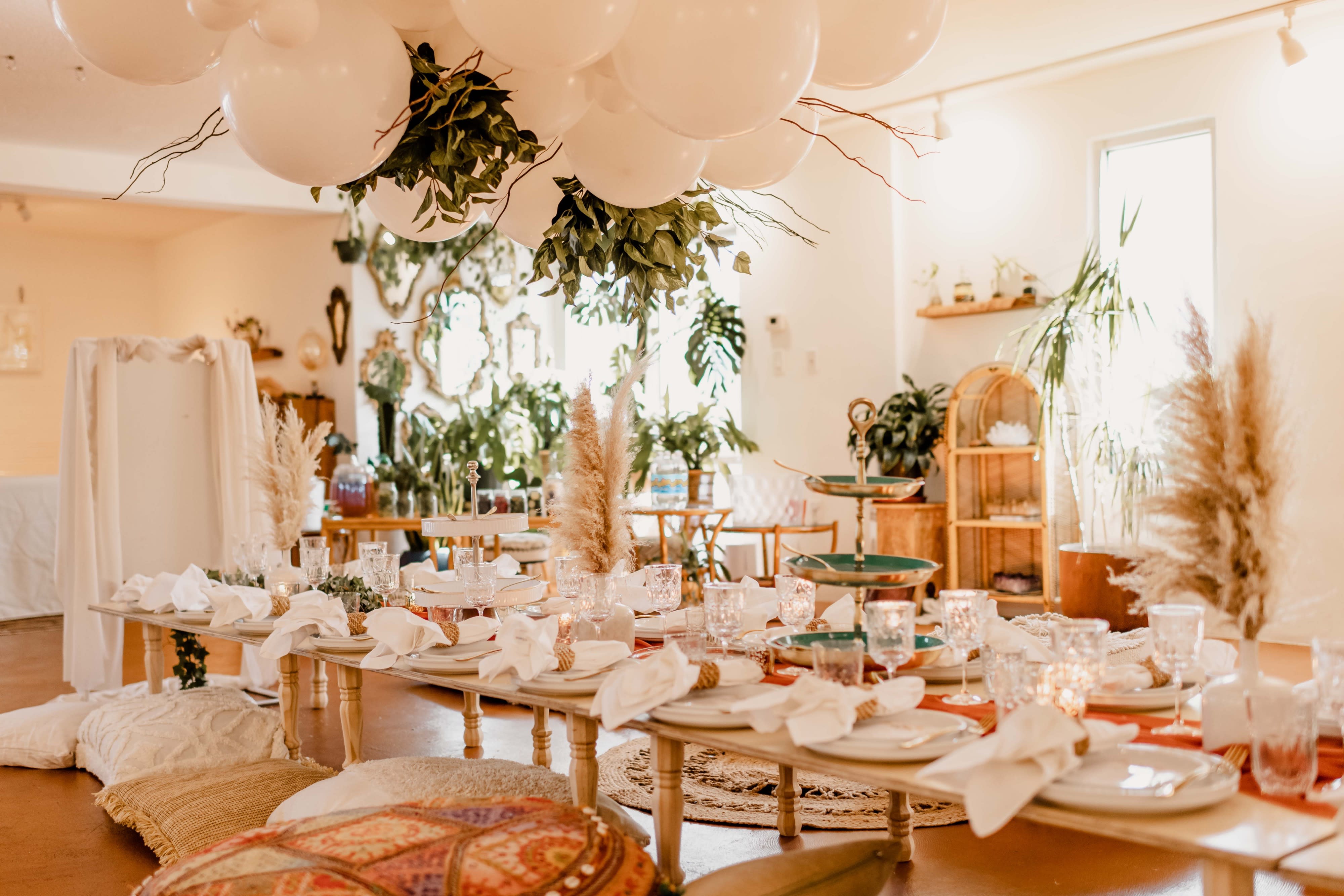 A decorative table is set up at a baby shower, featuring a welcome sign and adorned with a floral arrangement, surrounded by elegant mirrors and festive decorations.