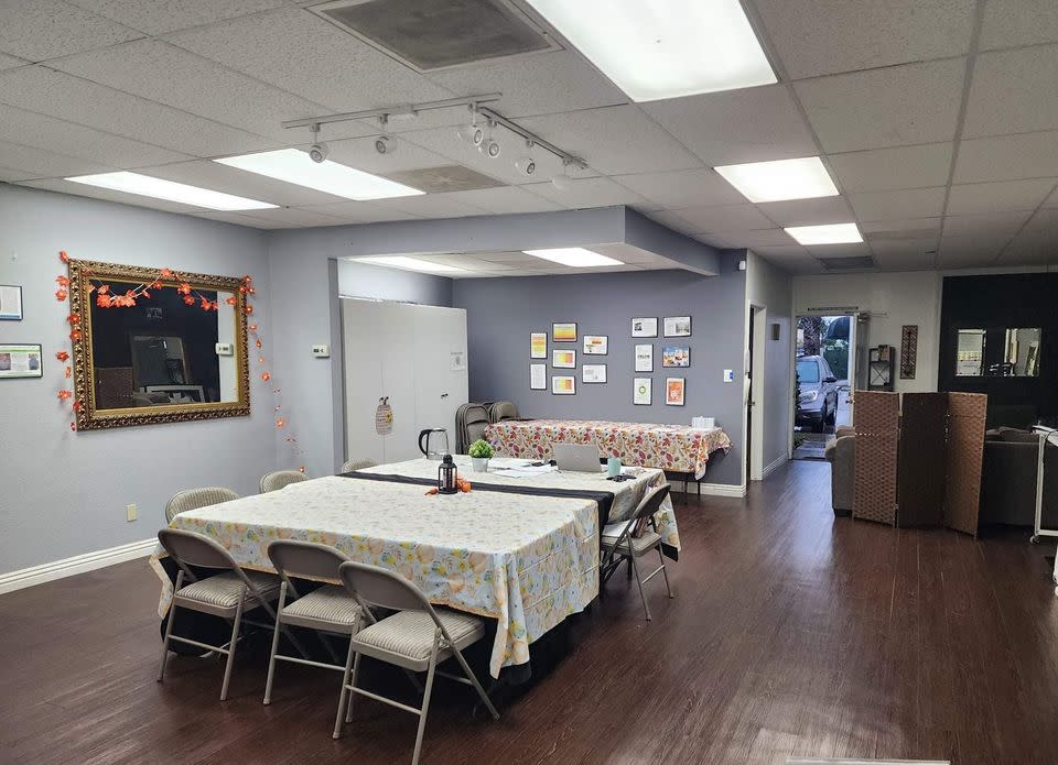 A group of participants is engaged in a paint and sip activity, each working on their own canvas in a spacious indoor setting.