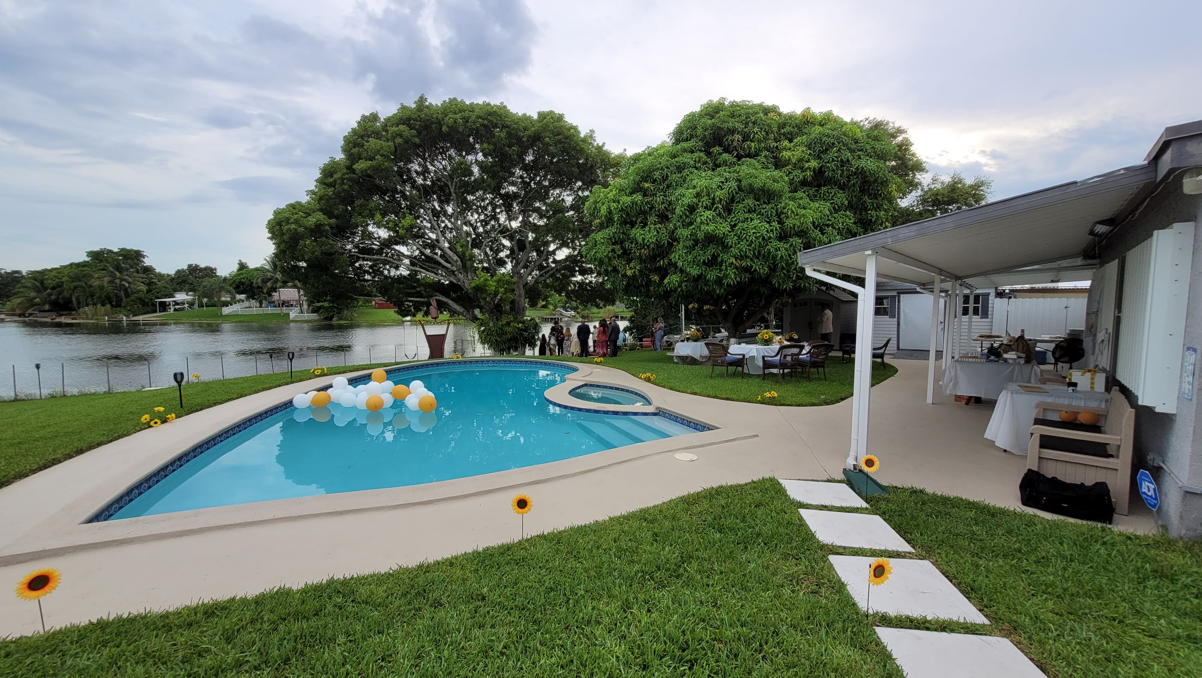 A decorated outdoor space features balloon sculptures and a sign for a baby shower beside a pool.