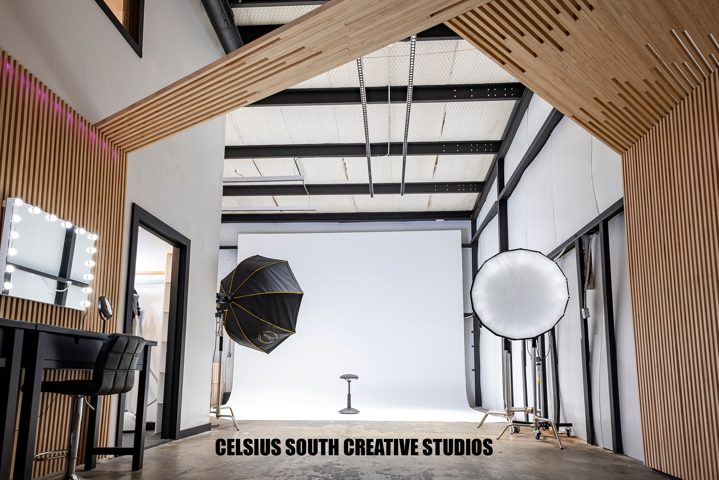 A photo shoot is taking place in a studio, featuring four individuals who are adjusting lighting and backdrops.