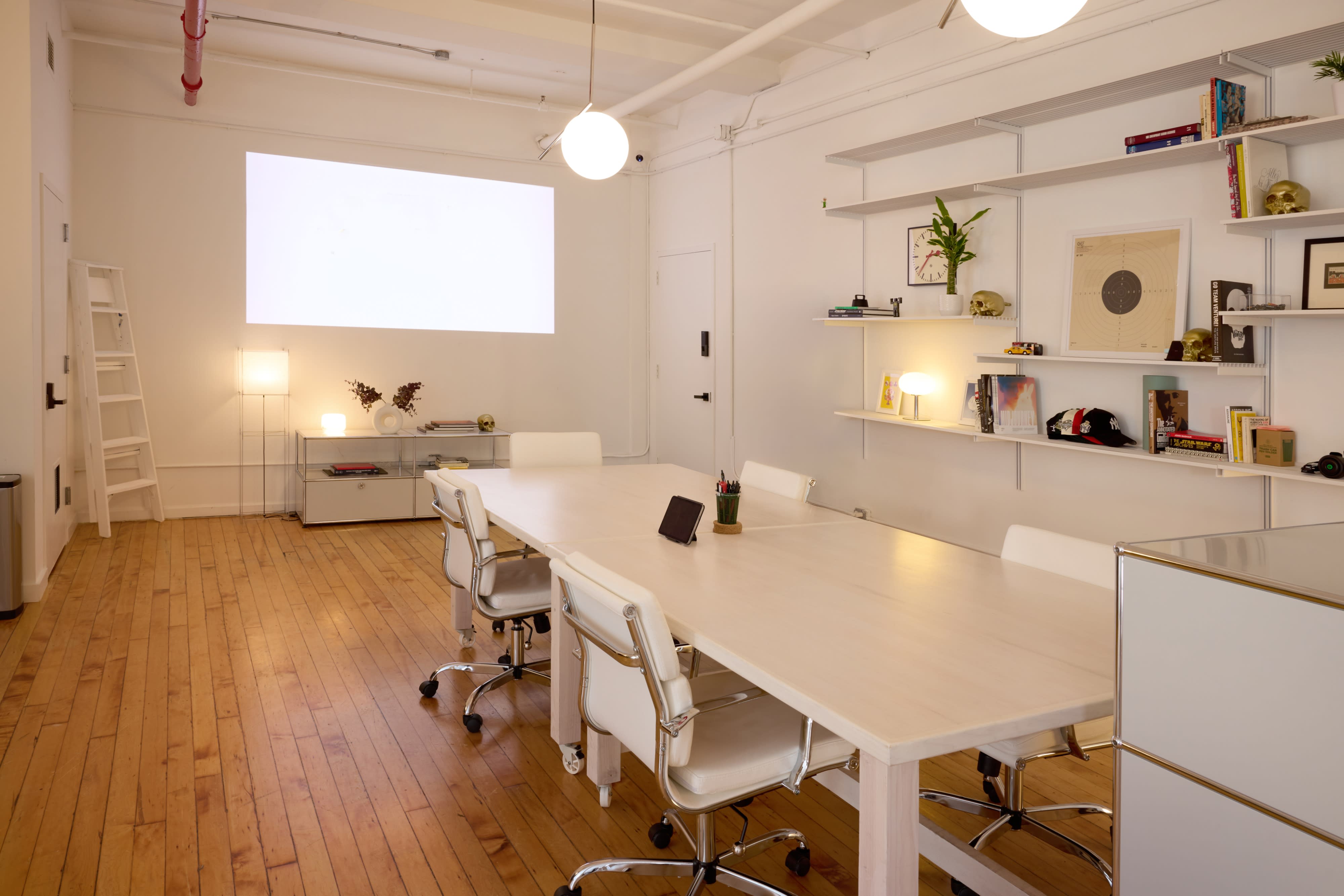 A corporate video shoot takes place in a spacious, empty room featuring piles of white material on the floor and large windows allowing natural light.