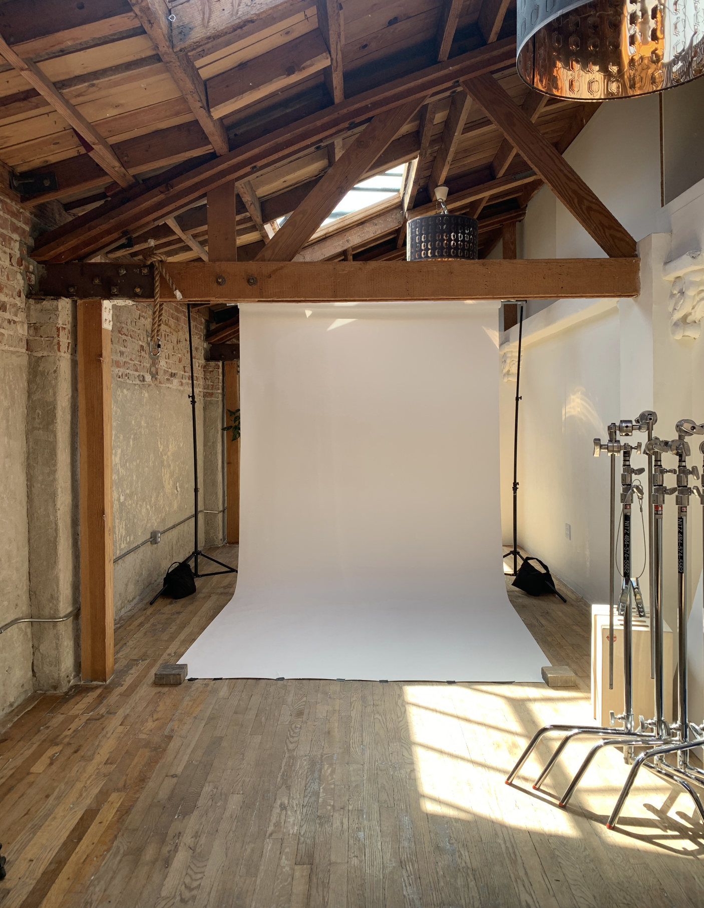 A woman stands in front of a colorful painting in an industrial space during a video shoot.