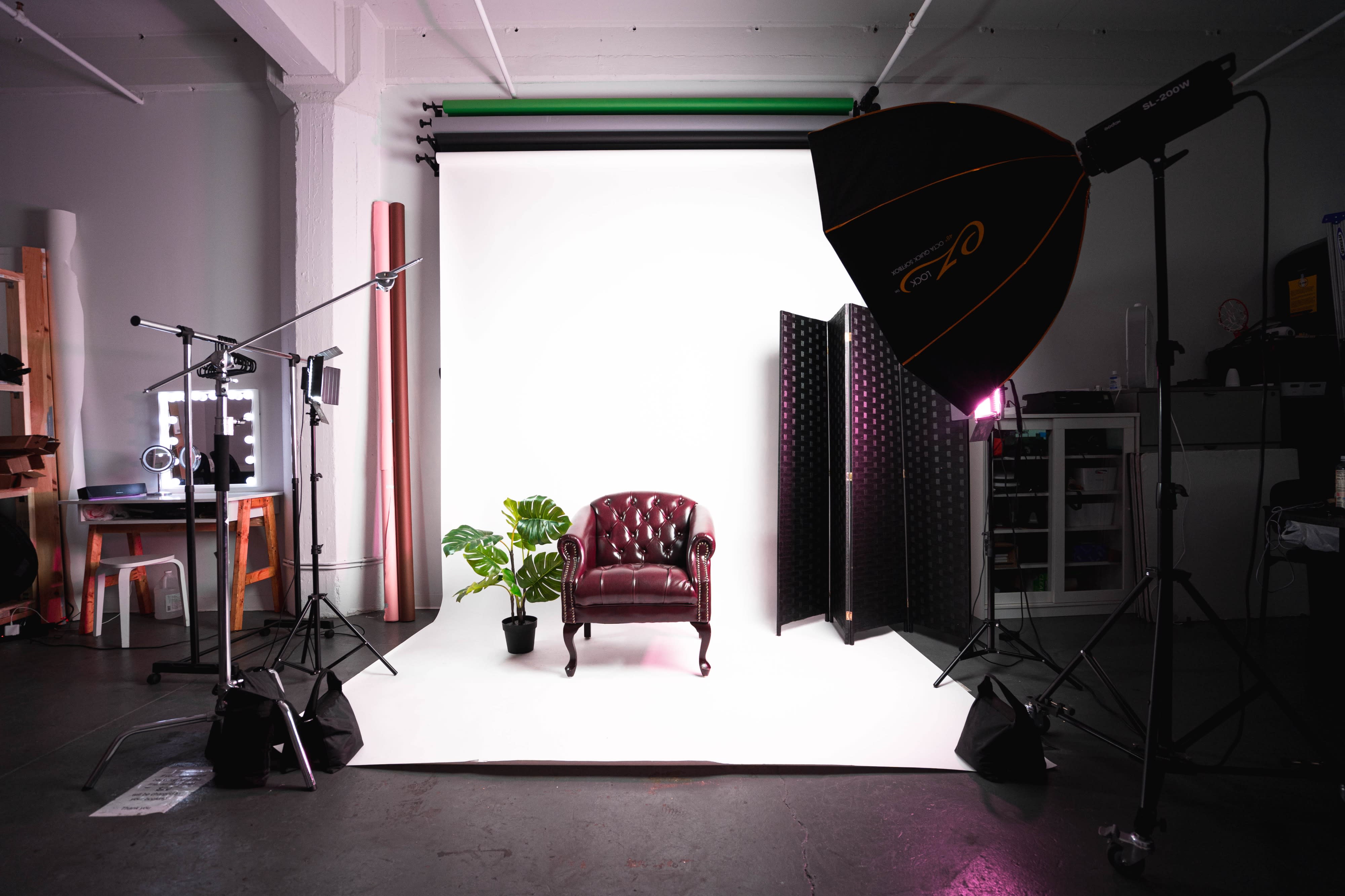 A model performs a handstand while wearing stylish, trendy attire against a purple backdrop during a photoshoot.