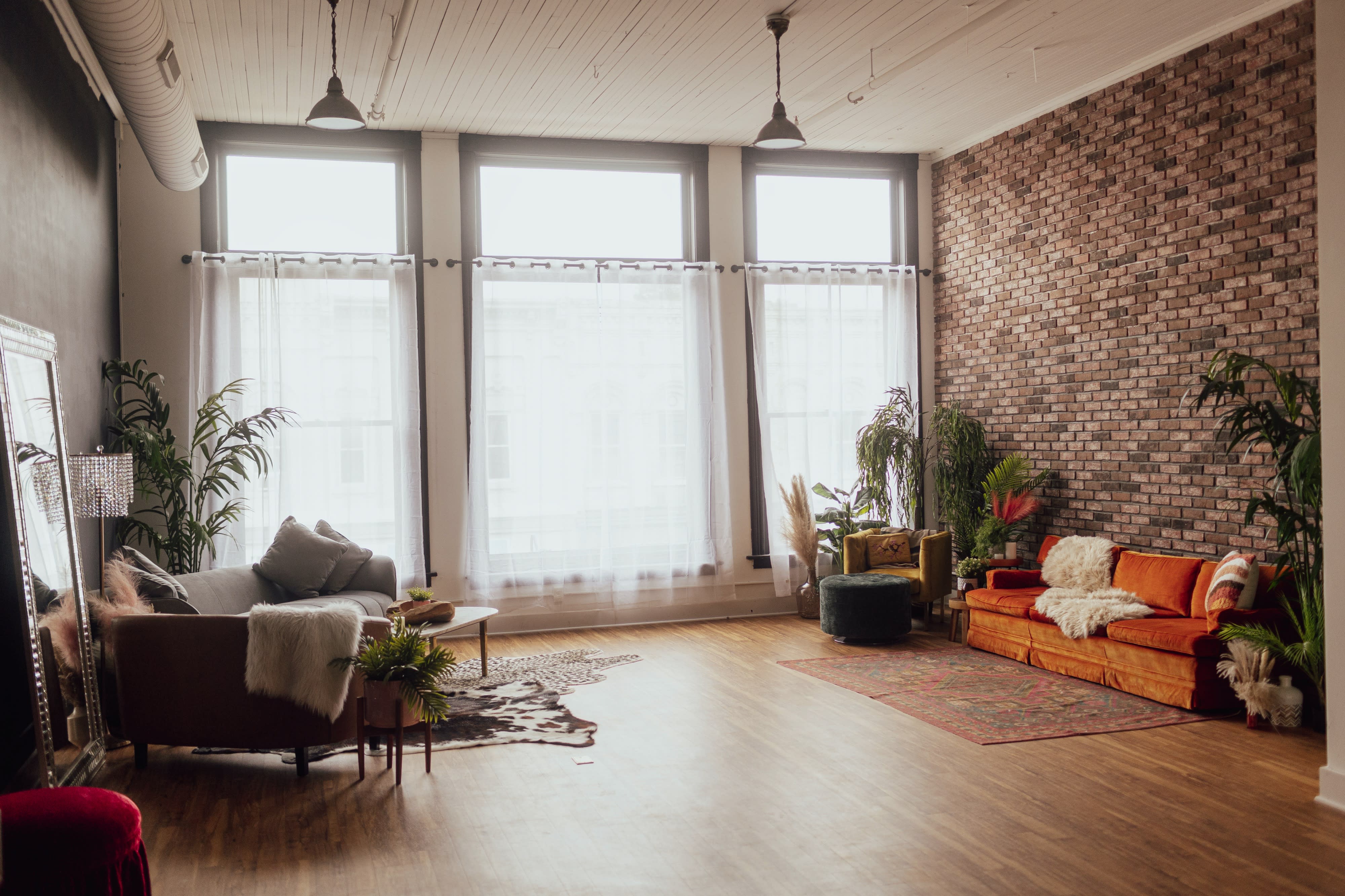 A spacious, minimalist studio features a bed, decorative elements, and colorful backdrops set for a brand photoshoot.