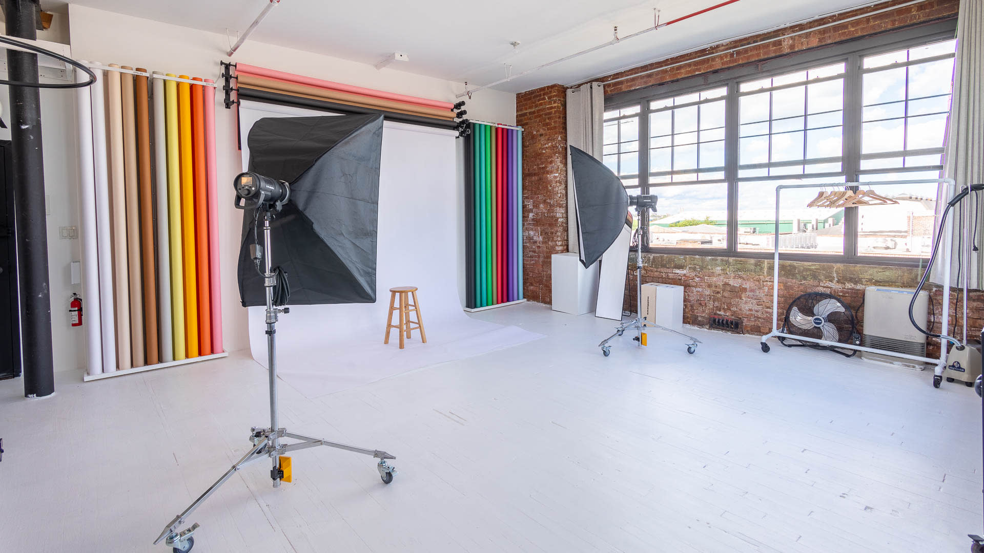 Three women hold promotional signs for a brand in a minimalist studio setting.