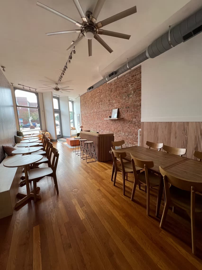 A group of women gathers in a bright, stylish café to celebrate a bridal shower.