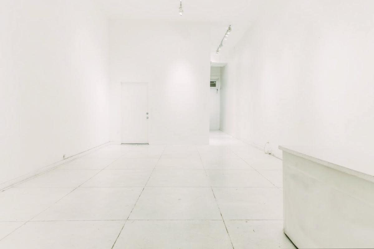 The image displays an art gallery featuring three large, abstract paintings arranged against a white wall.