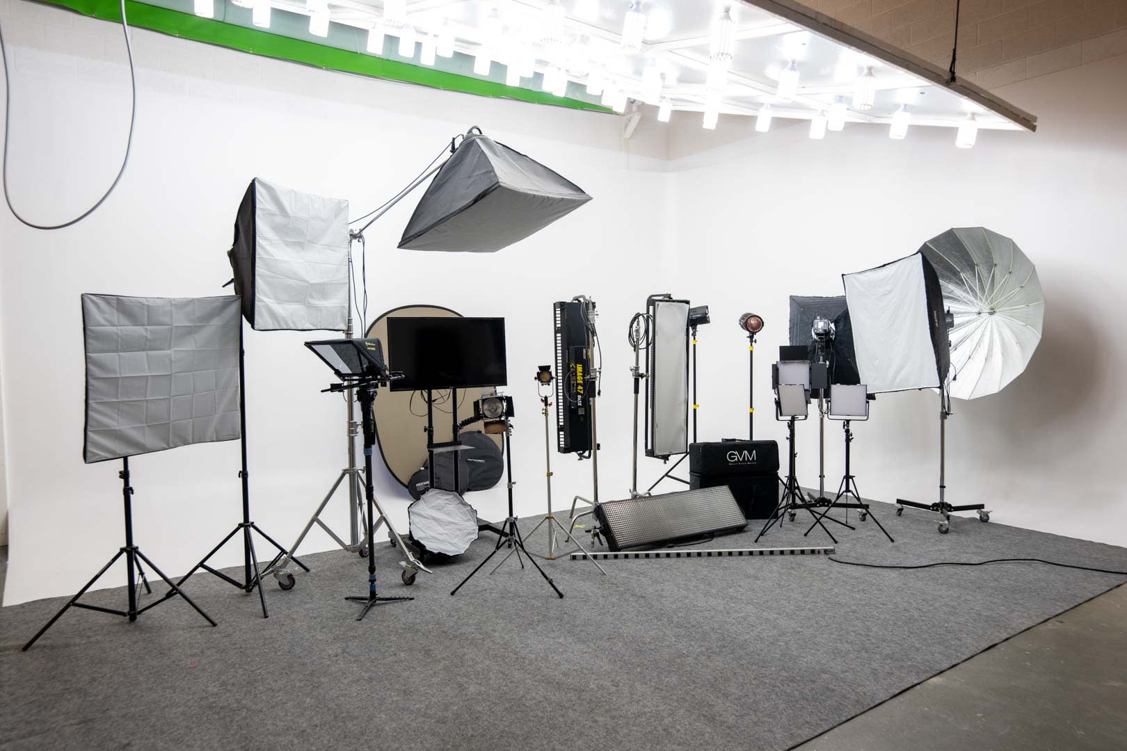 A cameraman operates a camera while an actress poses with a vintage television set in a well-lit studio.