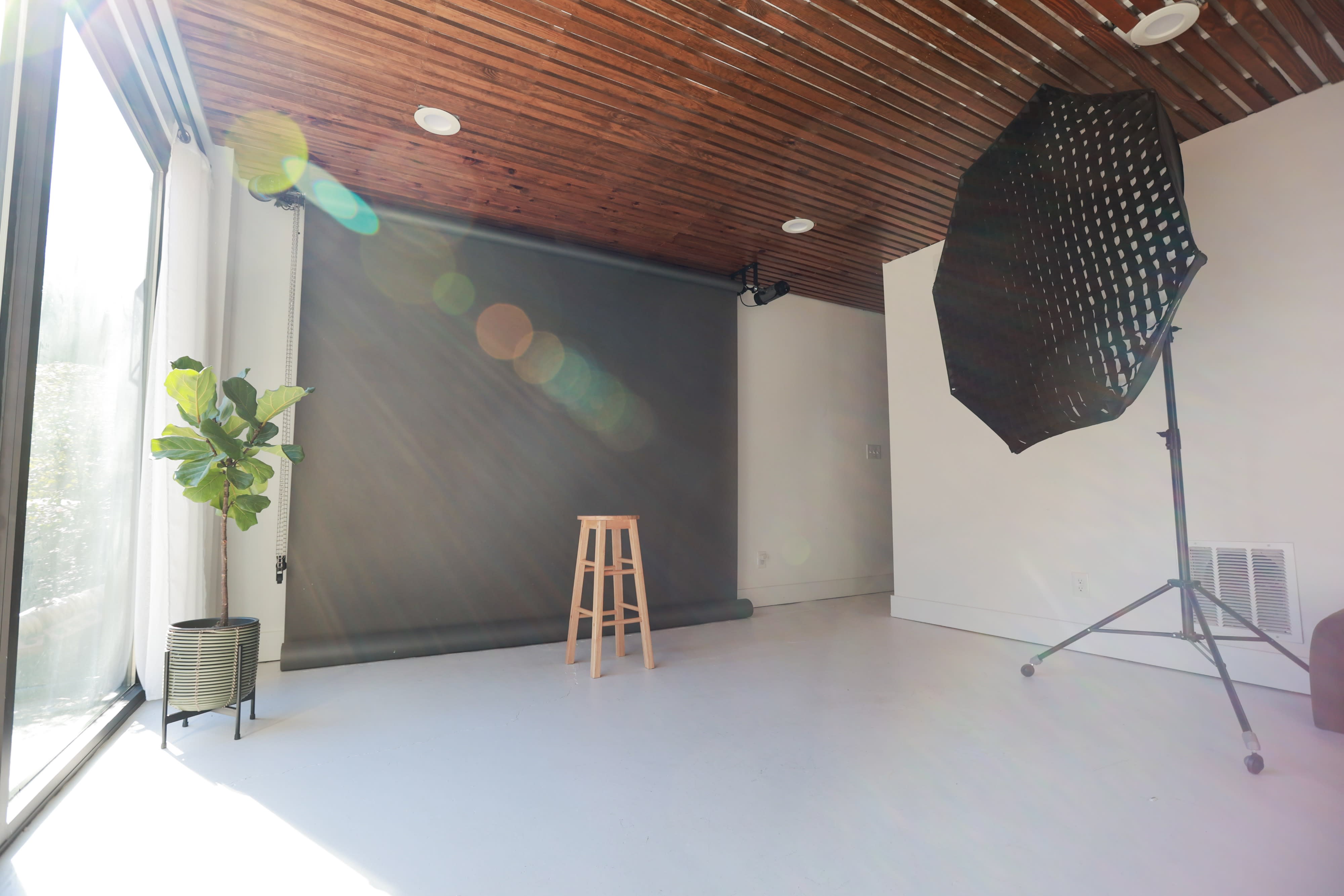 A photographer captures a model posing at a table in a well-lit studio.