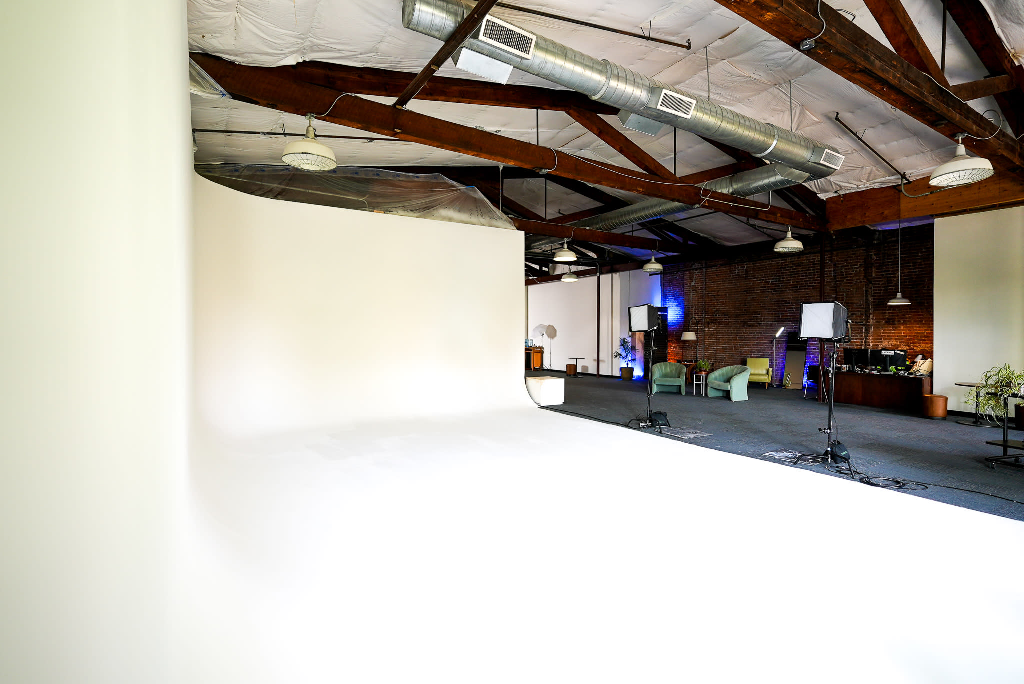 A person sits in a chair under a curved lamp in a softly lit room with exposed brick walls.