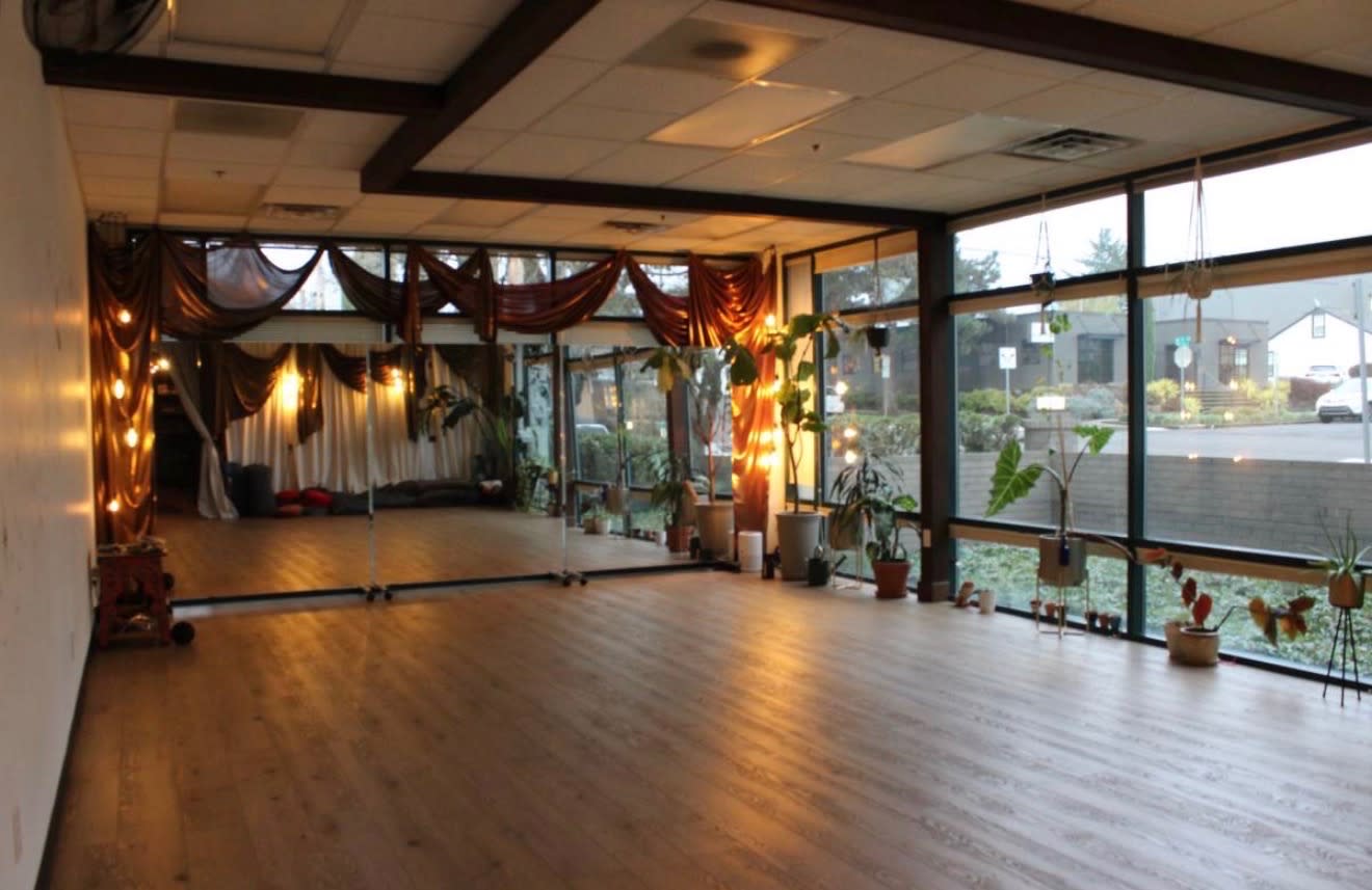 The workshop space is arranged with yoga mats and cushions in a circular layout, centered around a decorative stone arrangement.