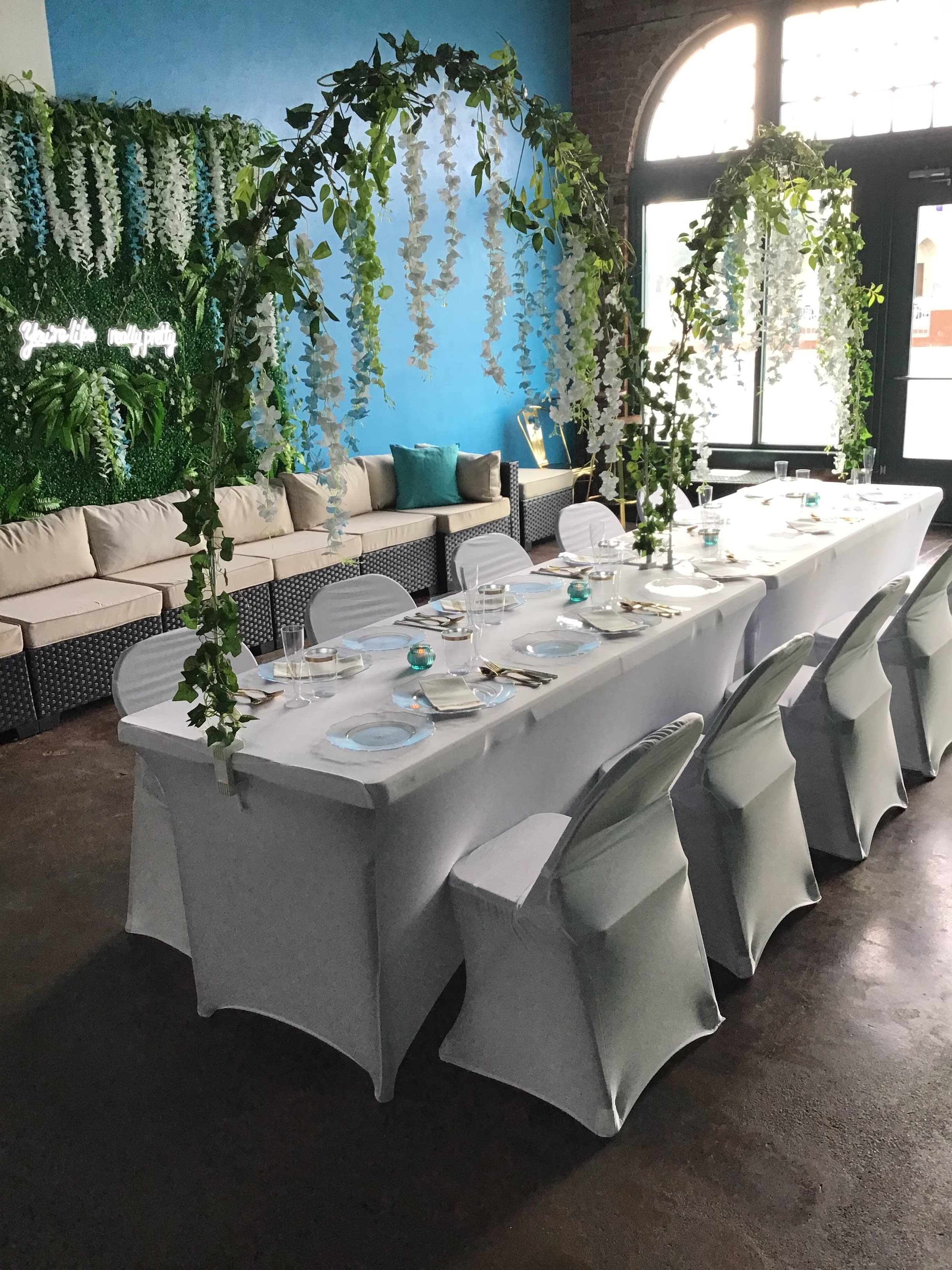 Guests gather around a table laden with food and decorations for a baby shower celebration in a festive room.