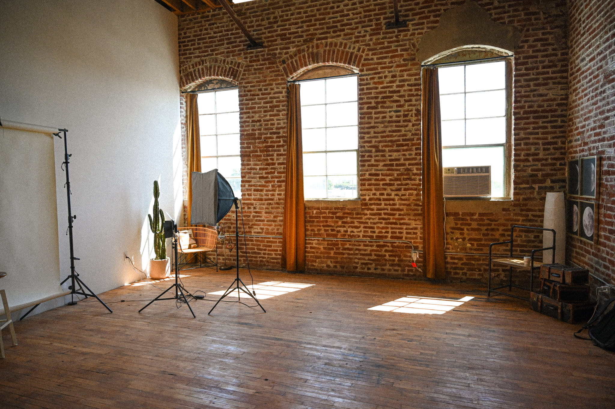 A model poses in a chair against a brick wall, showcasing moon prints and vintage suitcases in the background.