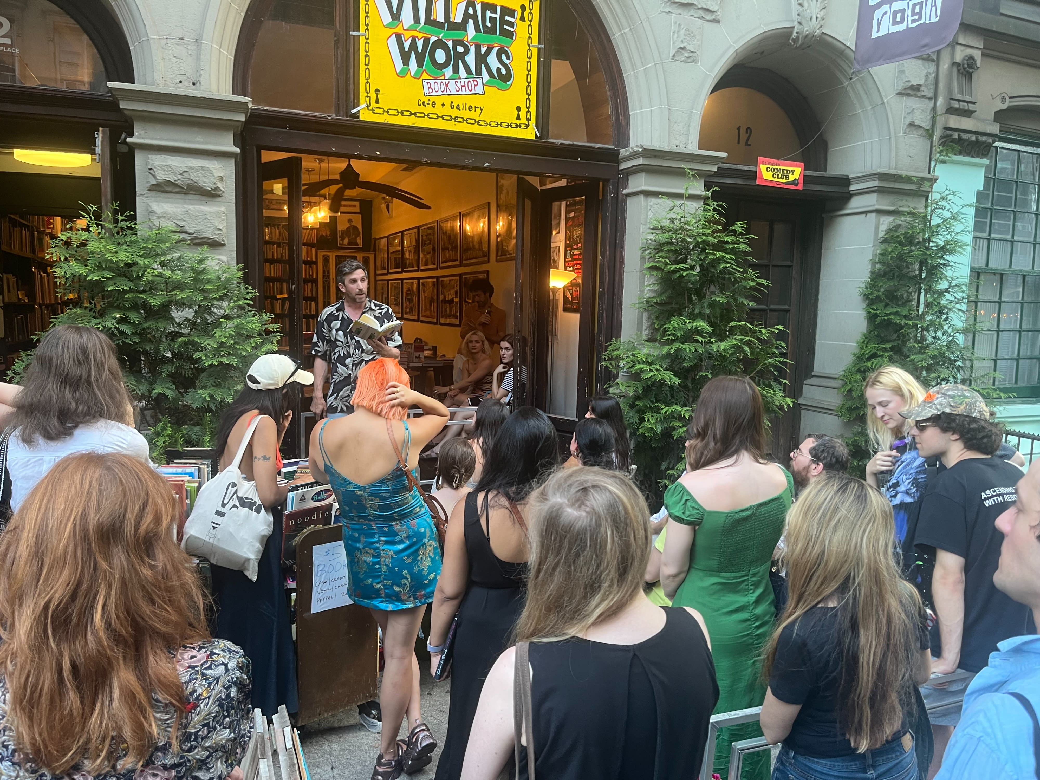 Two women walk by a charming storefront, one checking her phone while carrying a reusable tote bag.