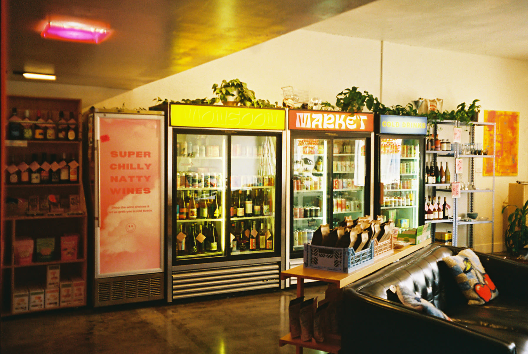 A model squats in front of a refrigerator displaying various beverages in a brightly lit store.