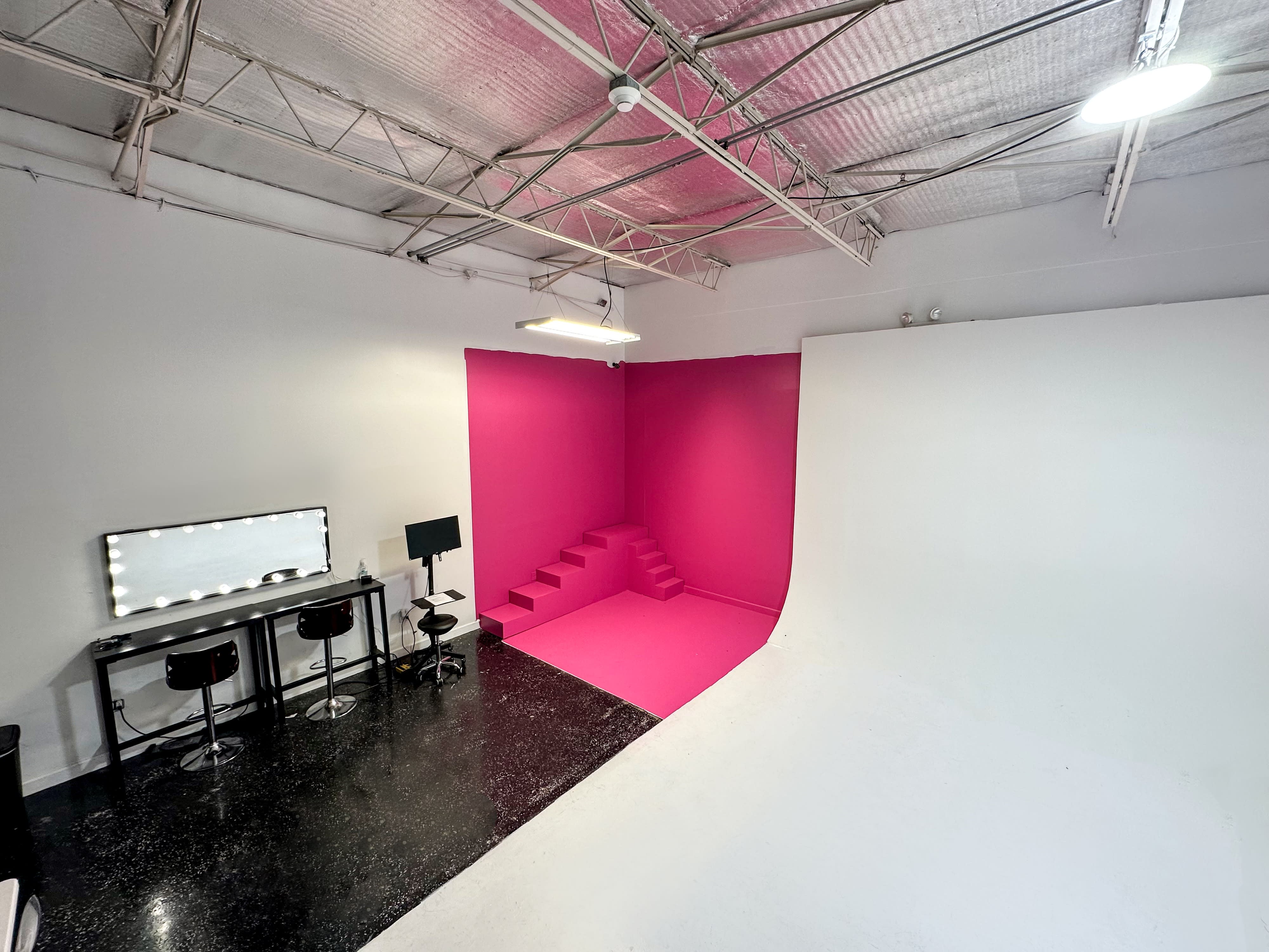 A model poses confidently in a studio while a photographer captures her image.