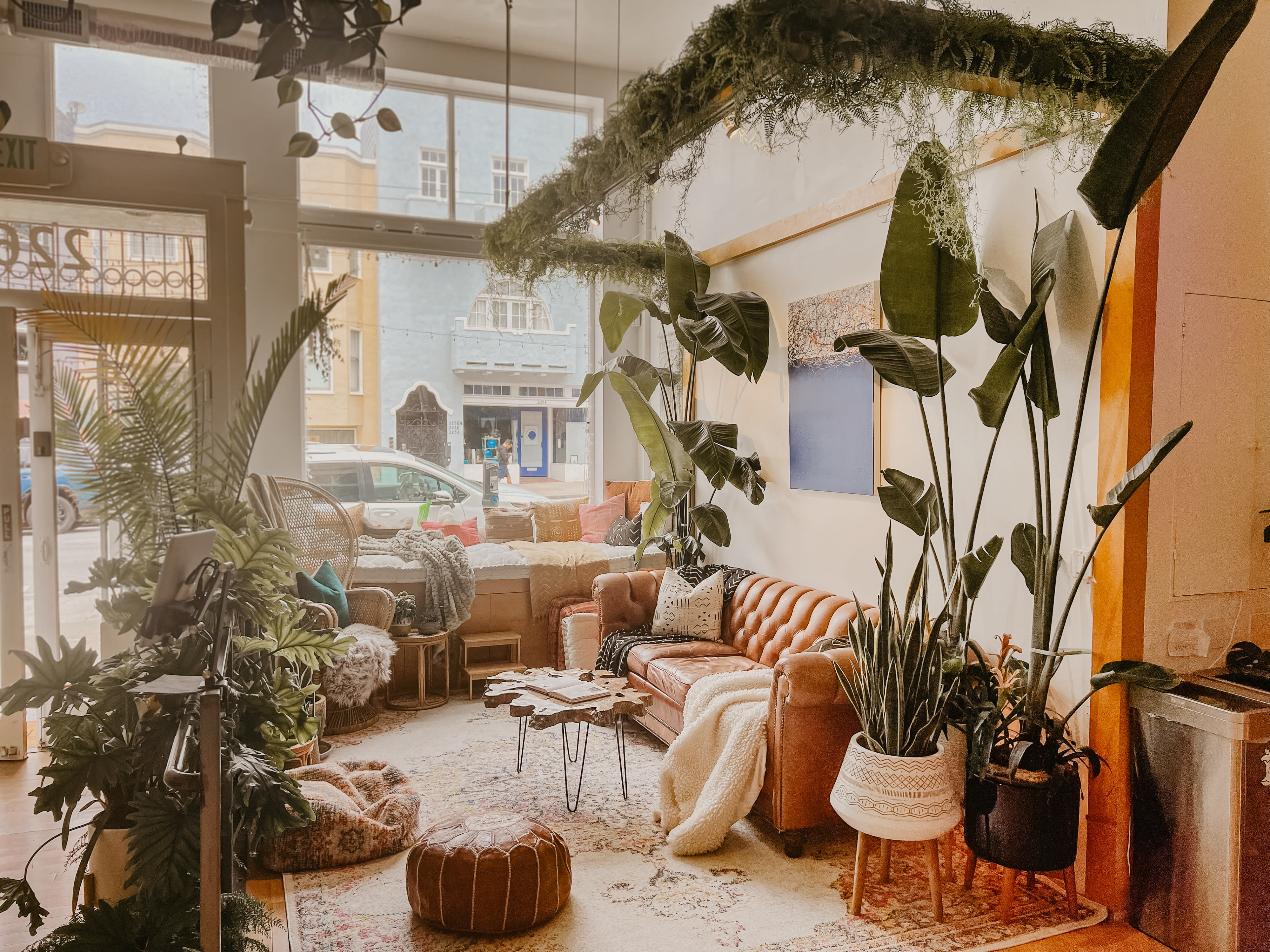 A barista prepares coffee at a vibrant café as guests relax on comfortable seating nearby.