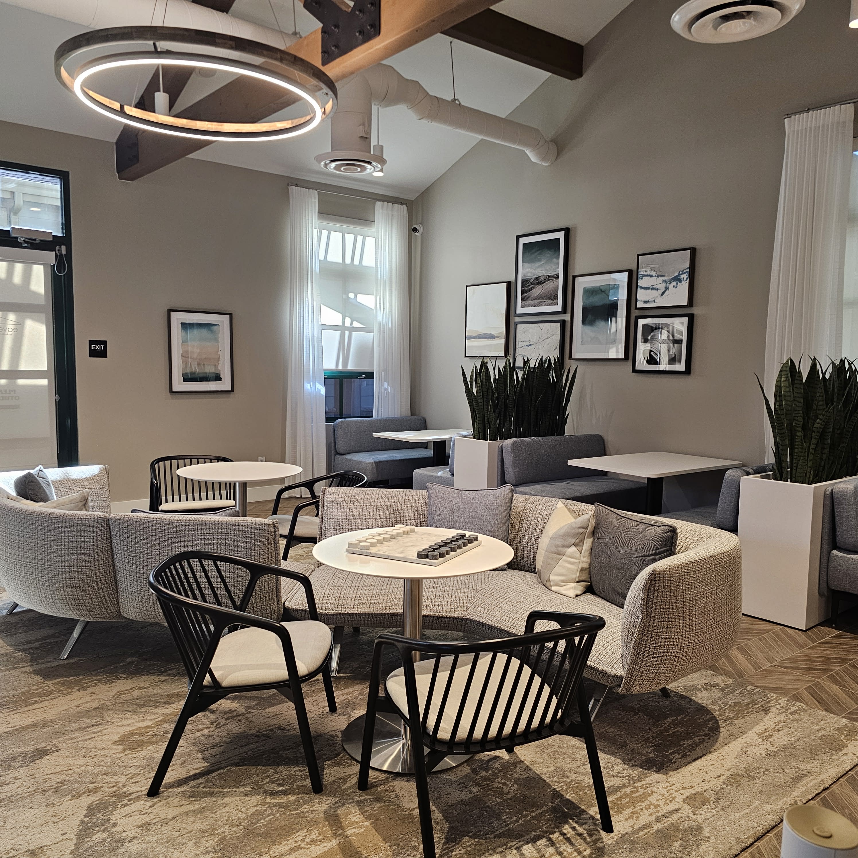 The image shows a modern indoor space with gray seating sections, decorated walls featuring artwork, and plants in the background, setting the scene for a birthday party.