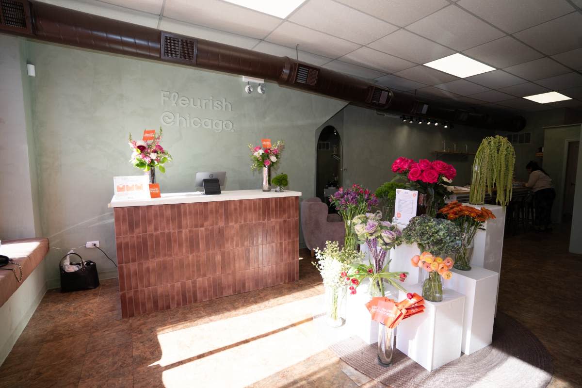 A group of women poses together inside Flourish Chicago, each holding a bouquet of flowers.