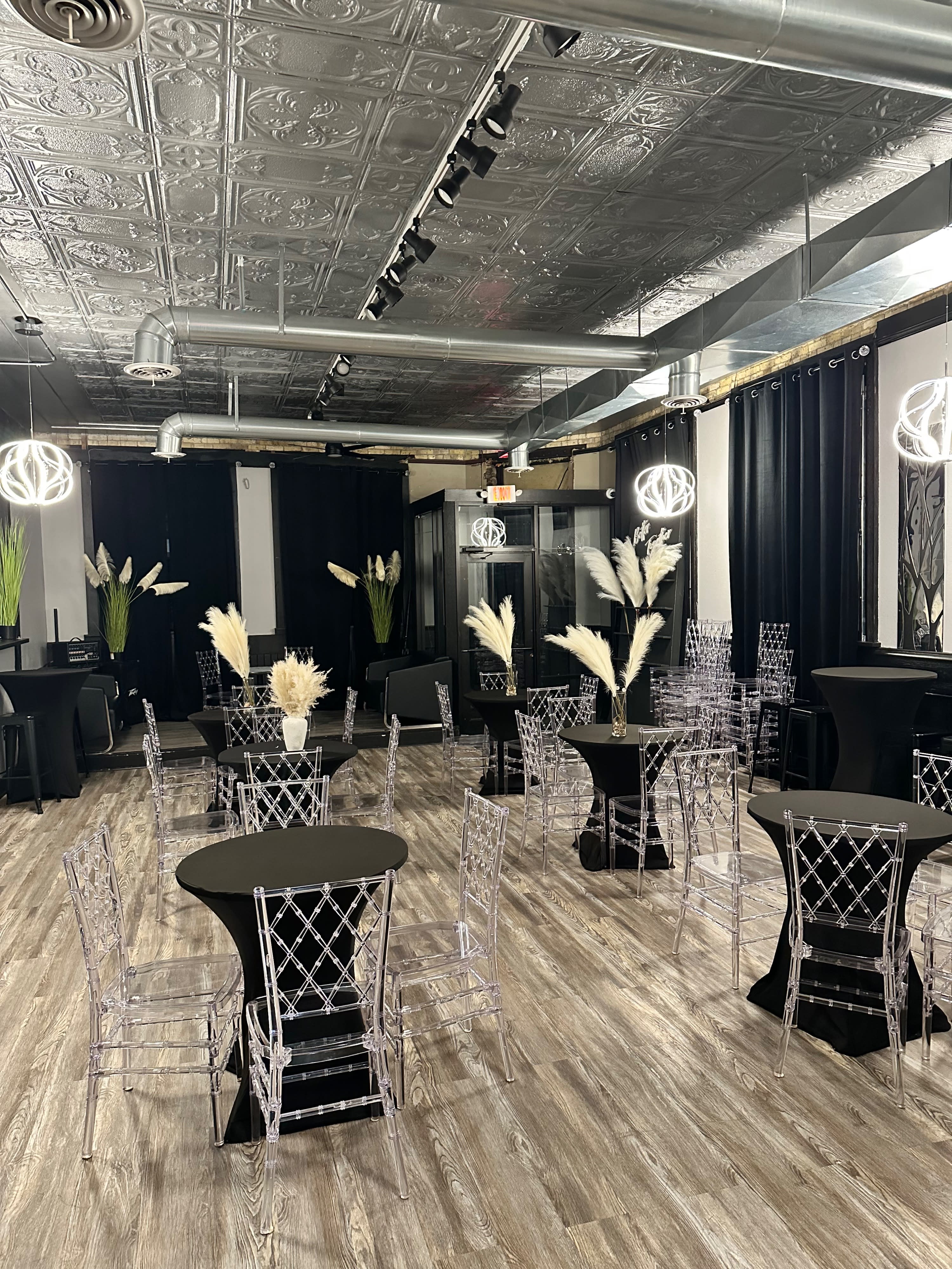 A long dining table is set for a birthday dinner, adorned with candles, black plates, and party hats, while balloons decorate the background.