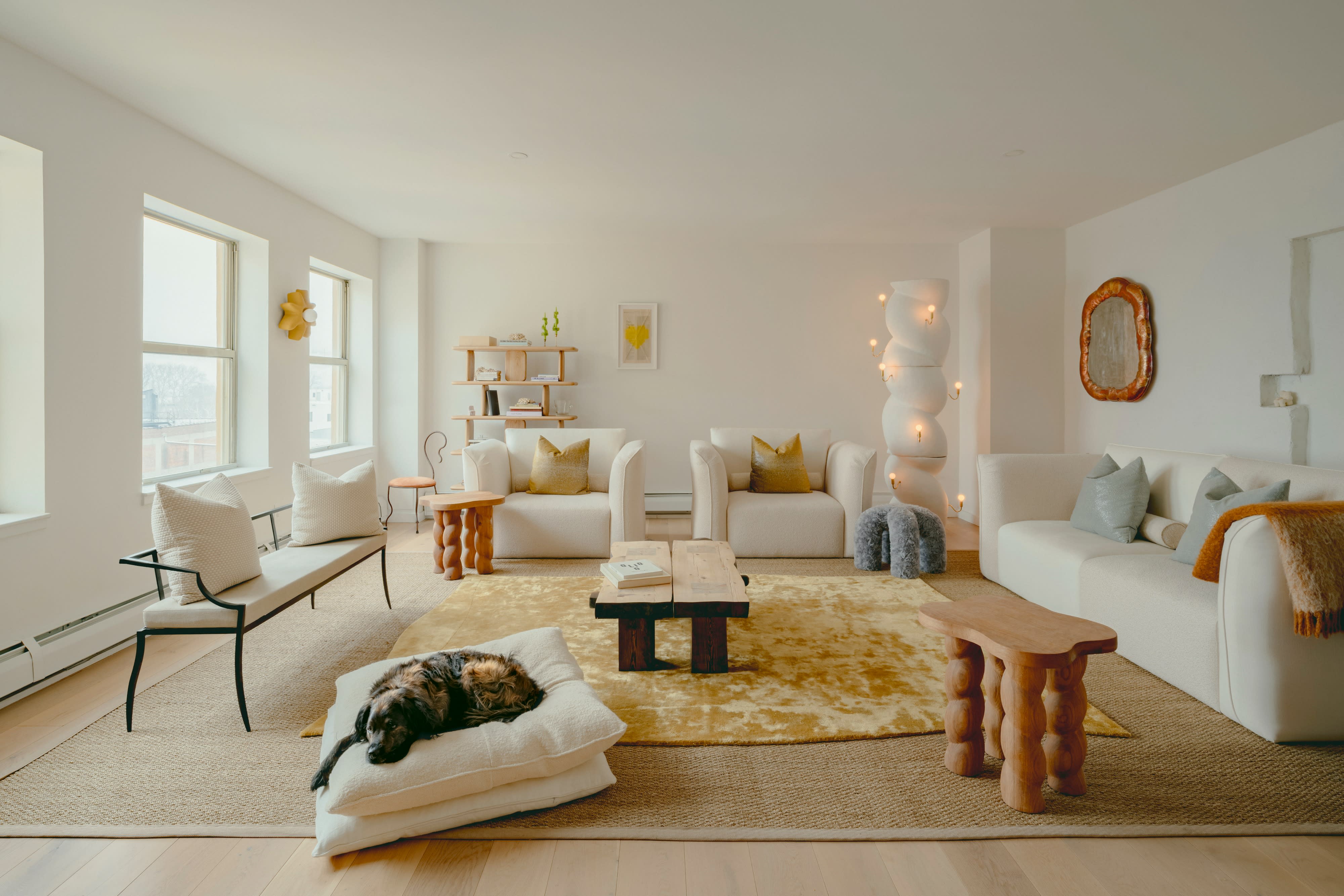 Two women engage in a lively conversation while posing for a photo shoot in a cozy, stylish living room.