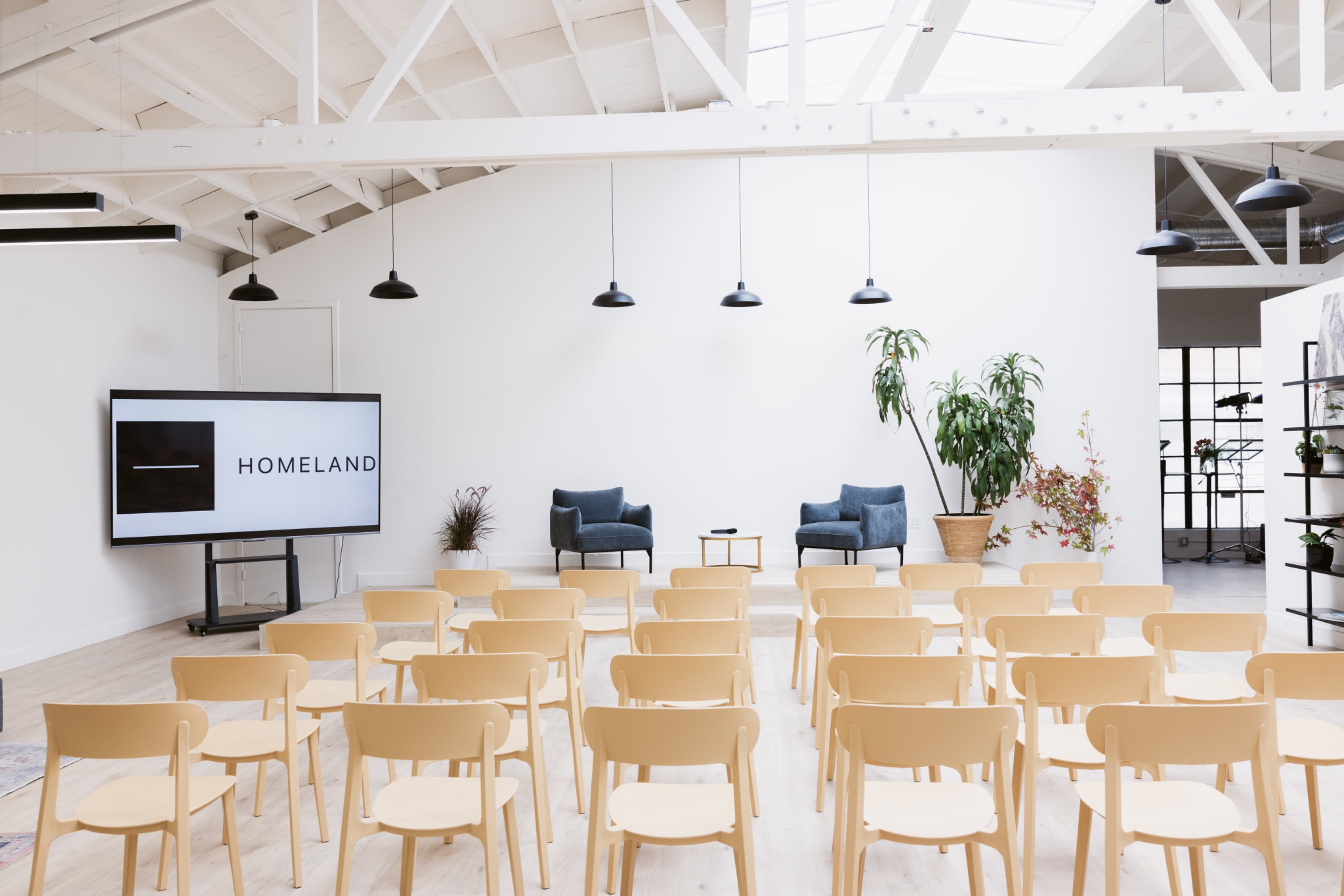 A group of panelists engages in a discussion in front of an audience seated in a modern, brightly lit space.
