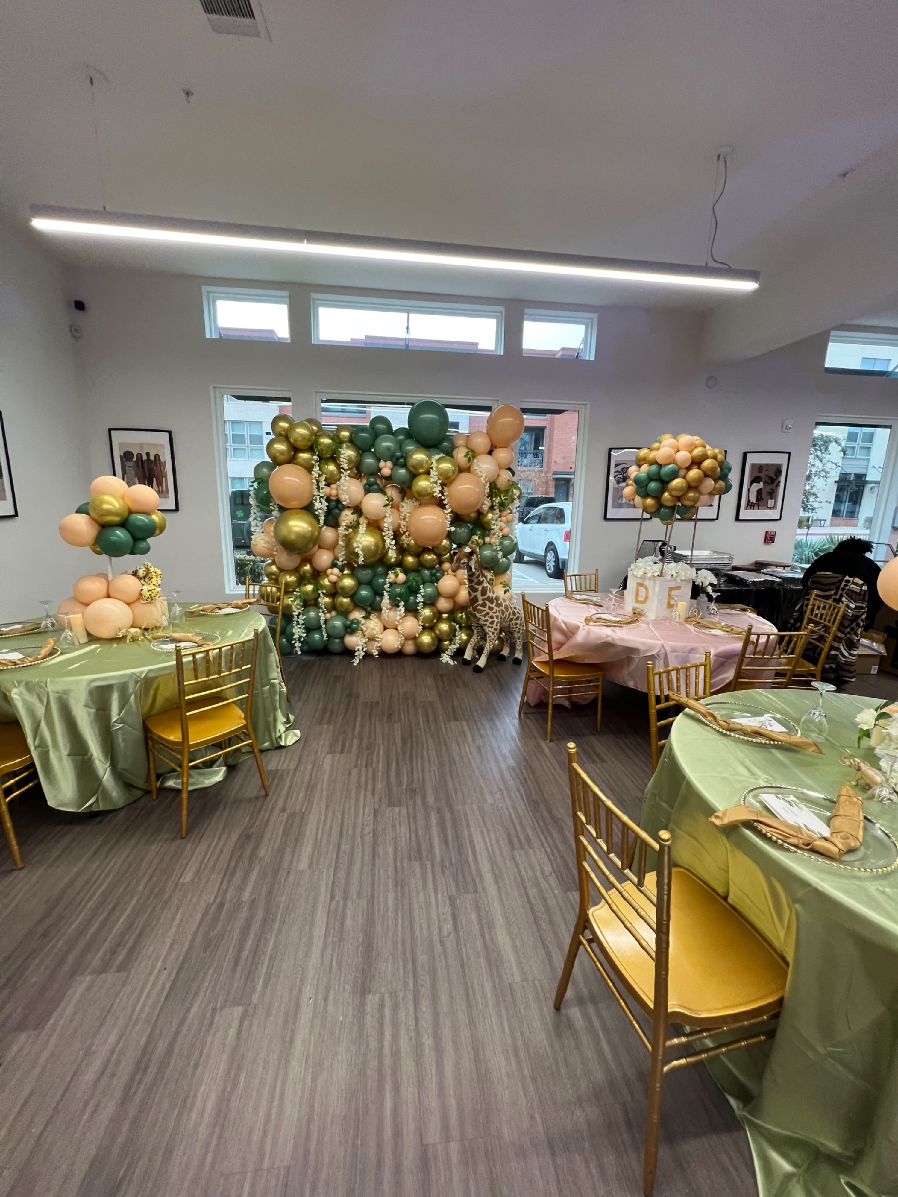 A buffet table displays an assortment of fruits, cheeses, and decorative glassware, set by a window overlooking a residential area.