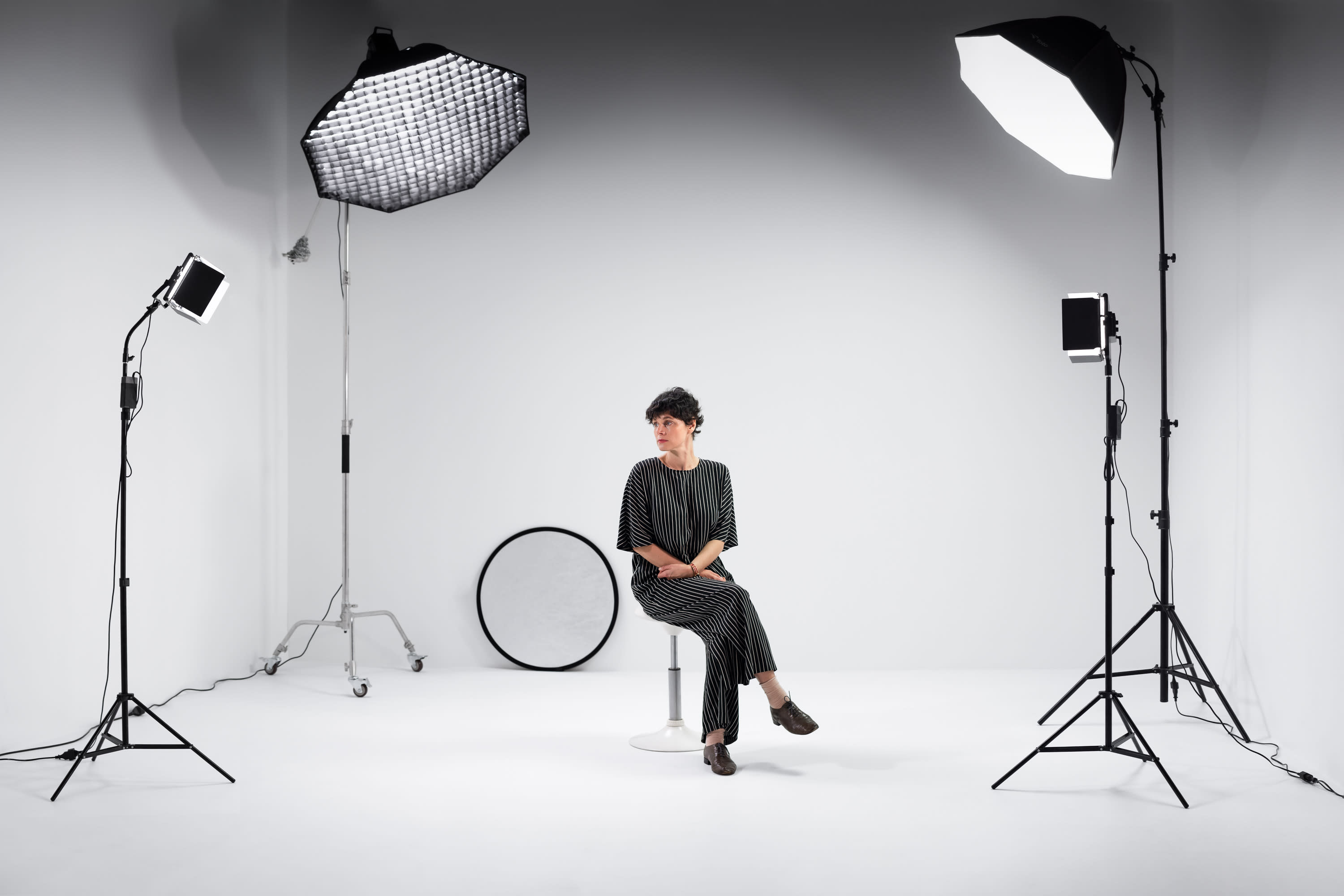 A model poses on the floor while a photographer captures the shot in a studio setting.