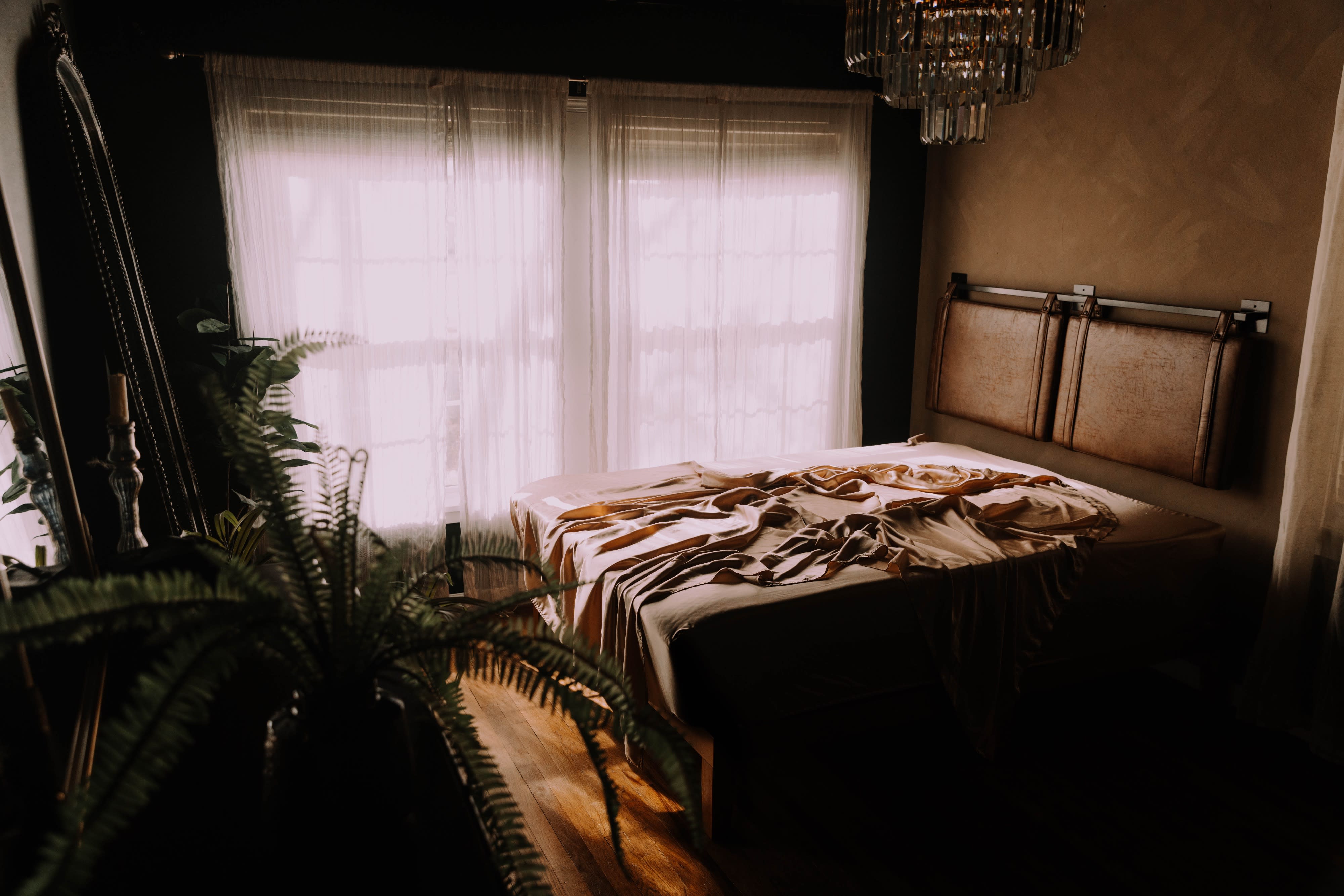 A pregnant woman poses thoughtfully while cradling her baby bump in a softly lit room.