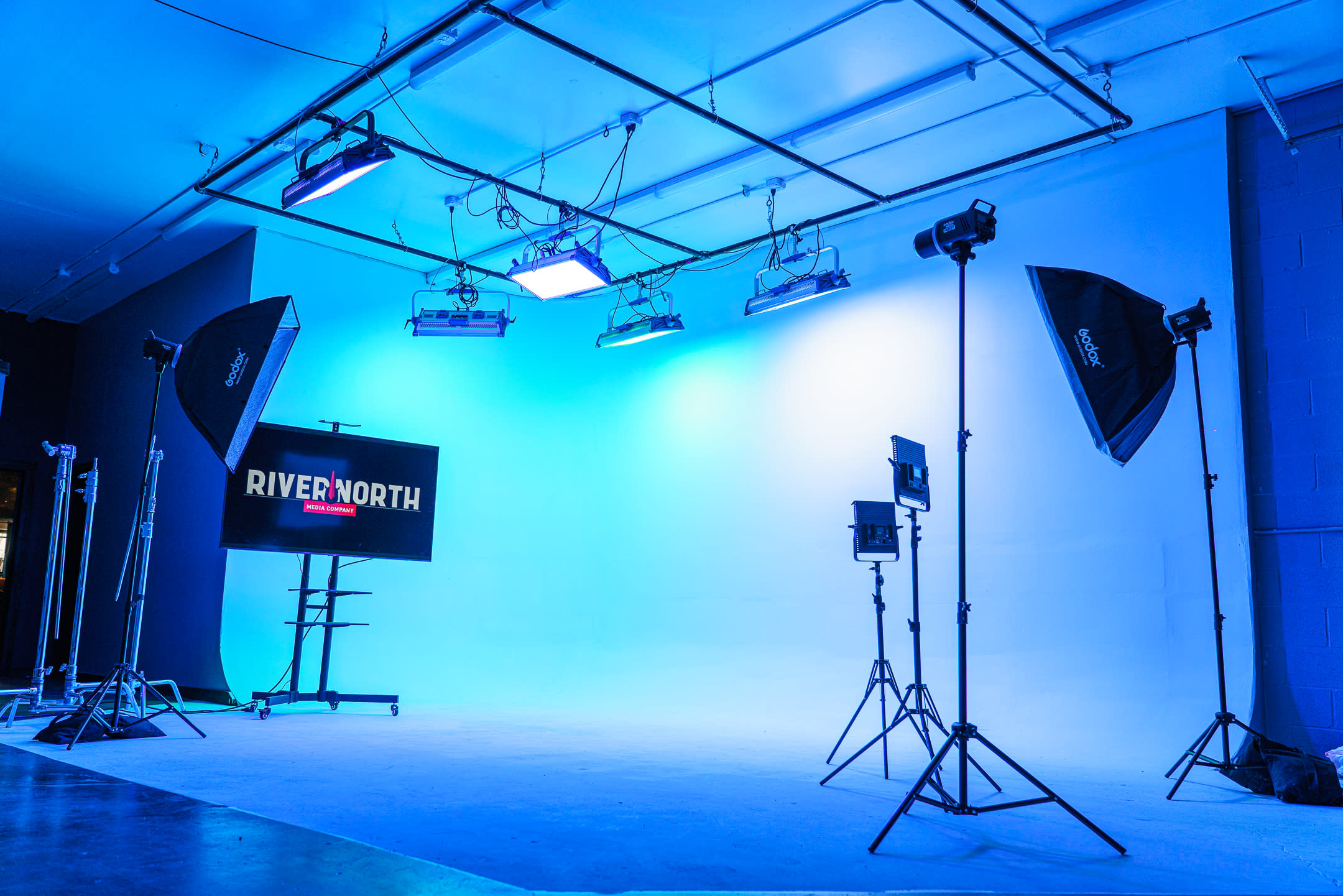 A group of six people is posing for a photoshoot in a studio with bright orange lighting.